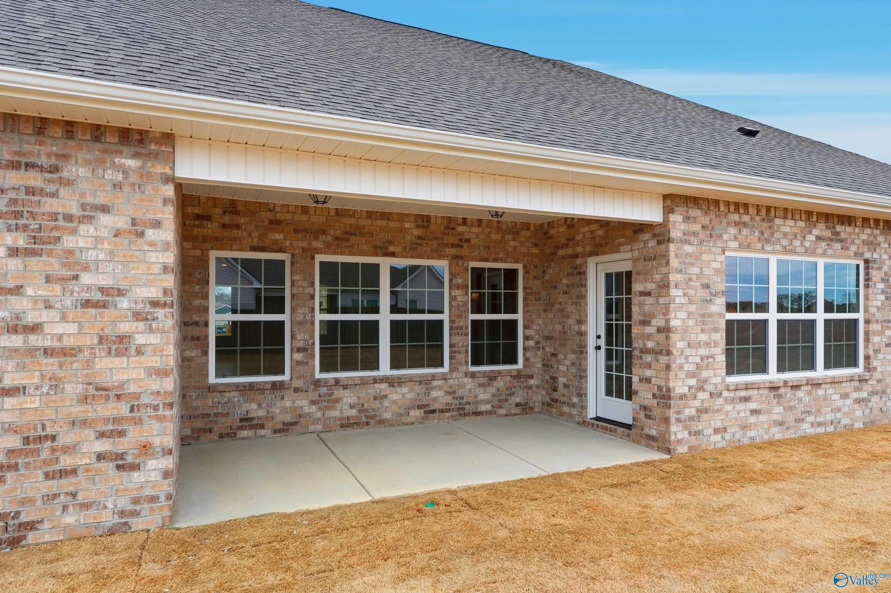 Covered back patio with brick exterior, large windows, and white door on The Finleigh home in Briercreek, Meridianville, Alabama
