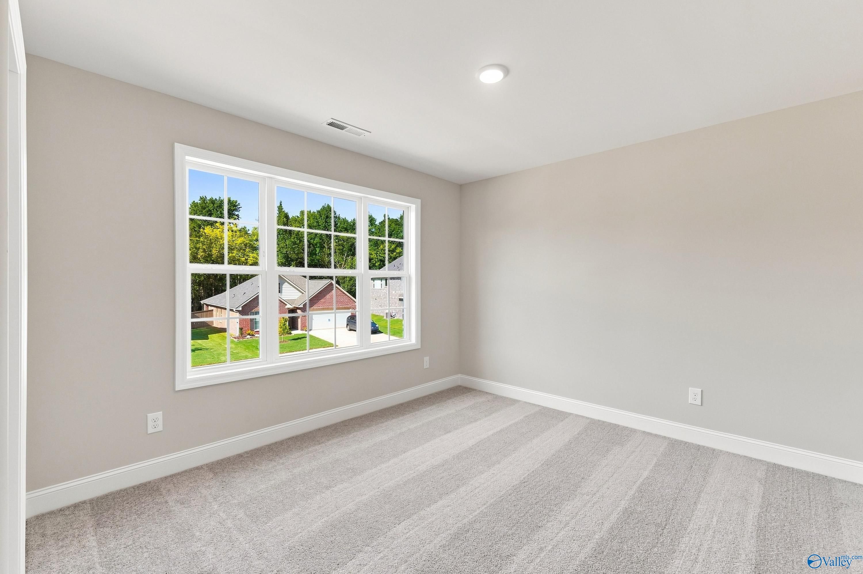 Bright carpeted bedroom with large window overlooking neighborhood in Davidson Homes The Chelsea B, New Market, Alabama