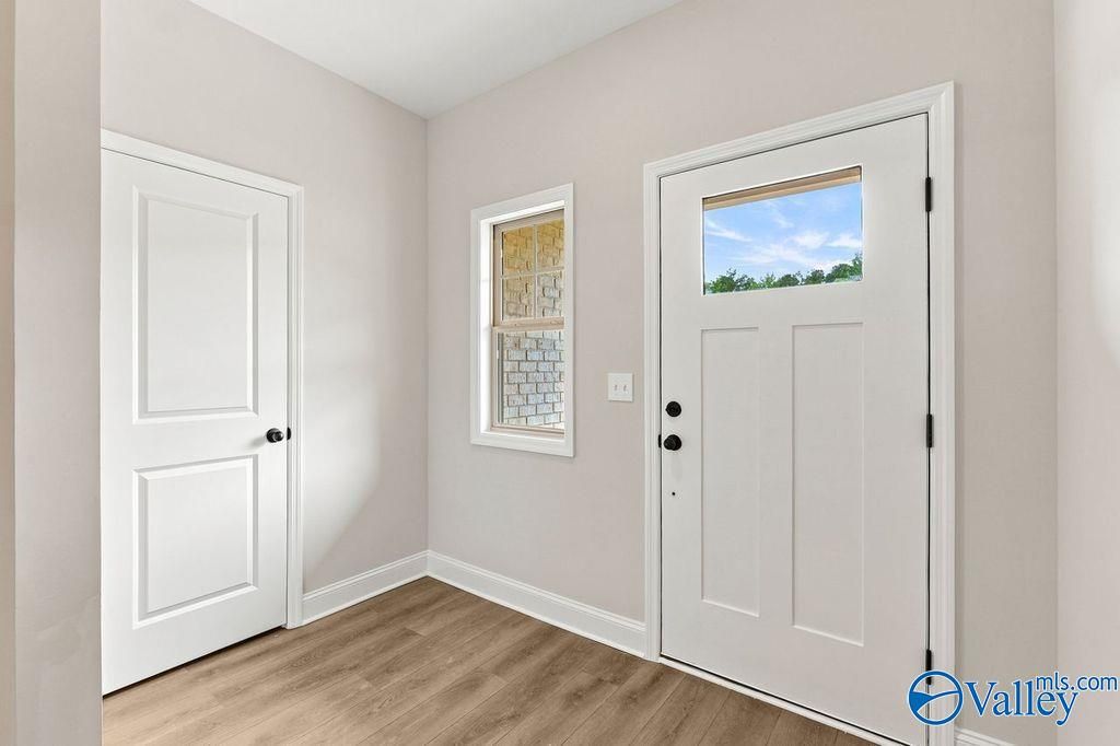Bright entryway with wood-style flooring and white front door in The Camilla C floor plan at The Retreat at Cain Park.