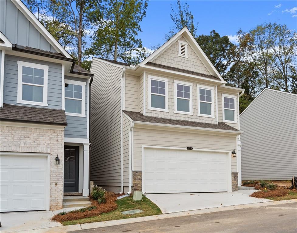Two-story Marion B home with 2-car garage, beige siding, and stone accents in The Village at Shallowford, Kennesaw, Georgia