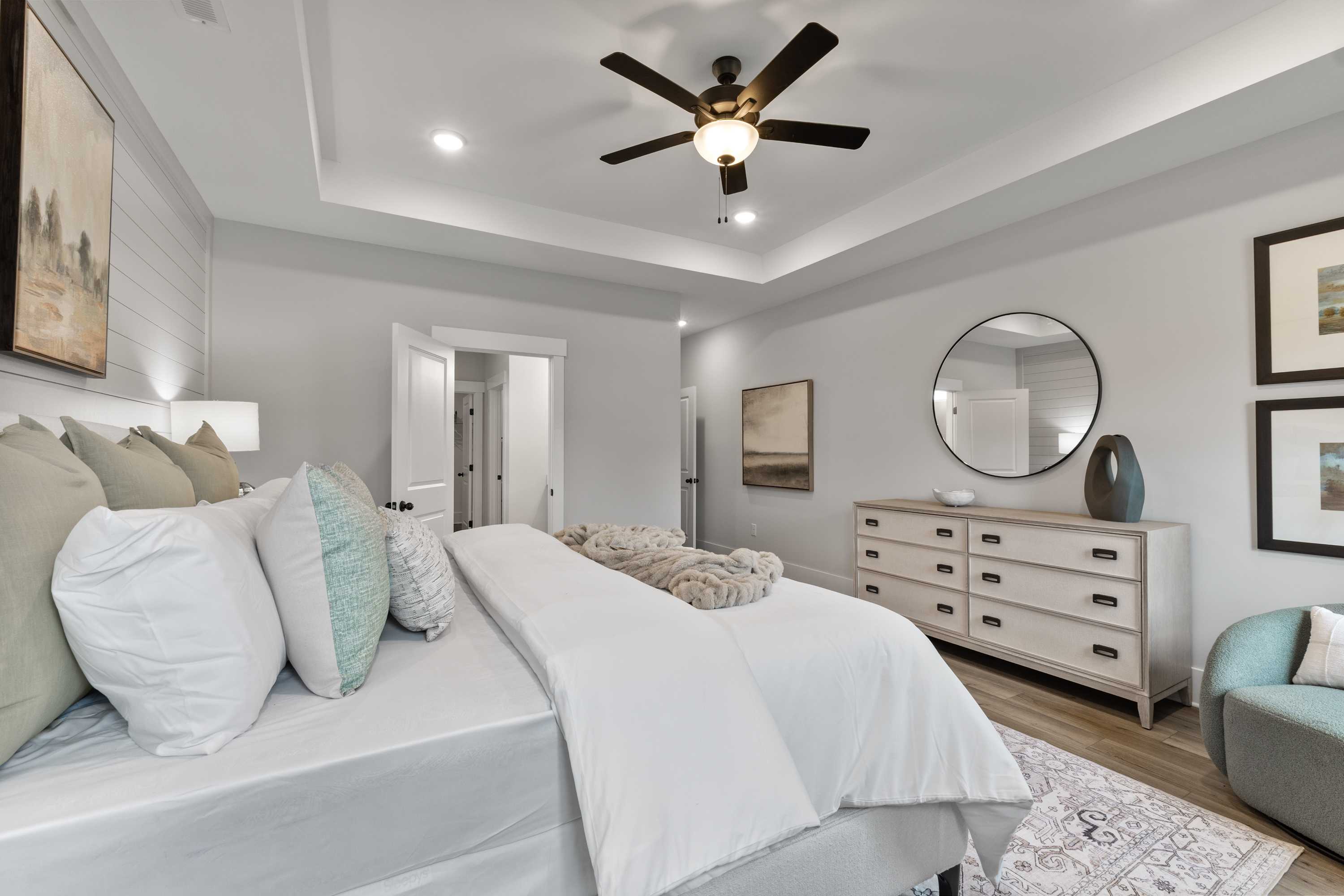 Spacious master bedroom at River Road Estates in Decatur Alabama with gray walls, king bed, ceiling fan, and wooden dresser