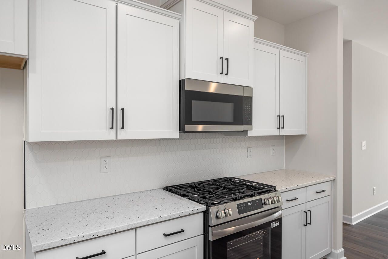 Modern kitchen with white cabinets, granite countertops, and stainless steel appliances in The Mitchell floor plan.