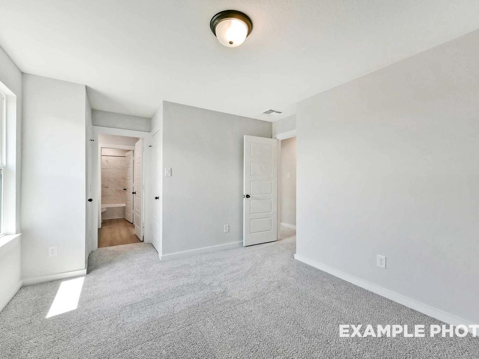Bright bedroom with plush carpet and en-suite bathroom in The Sequoia C floor plan by Davidson Homes in Crosby, Texas.