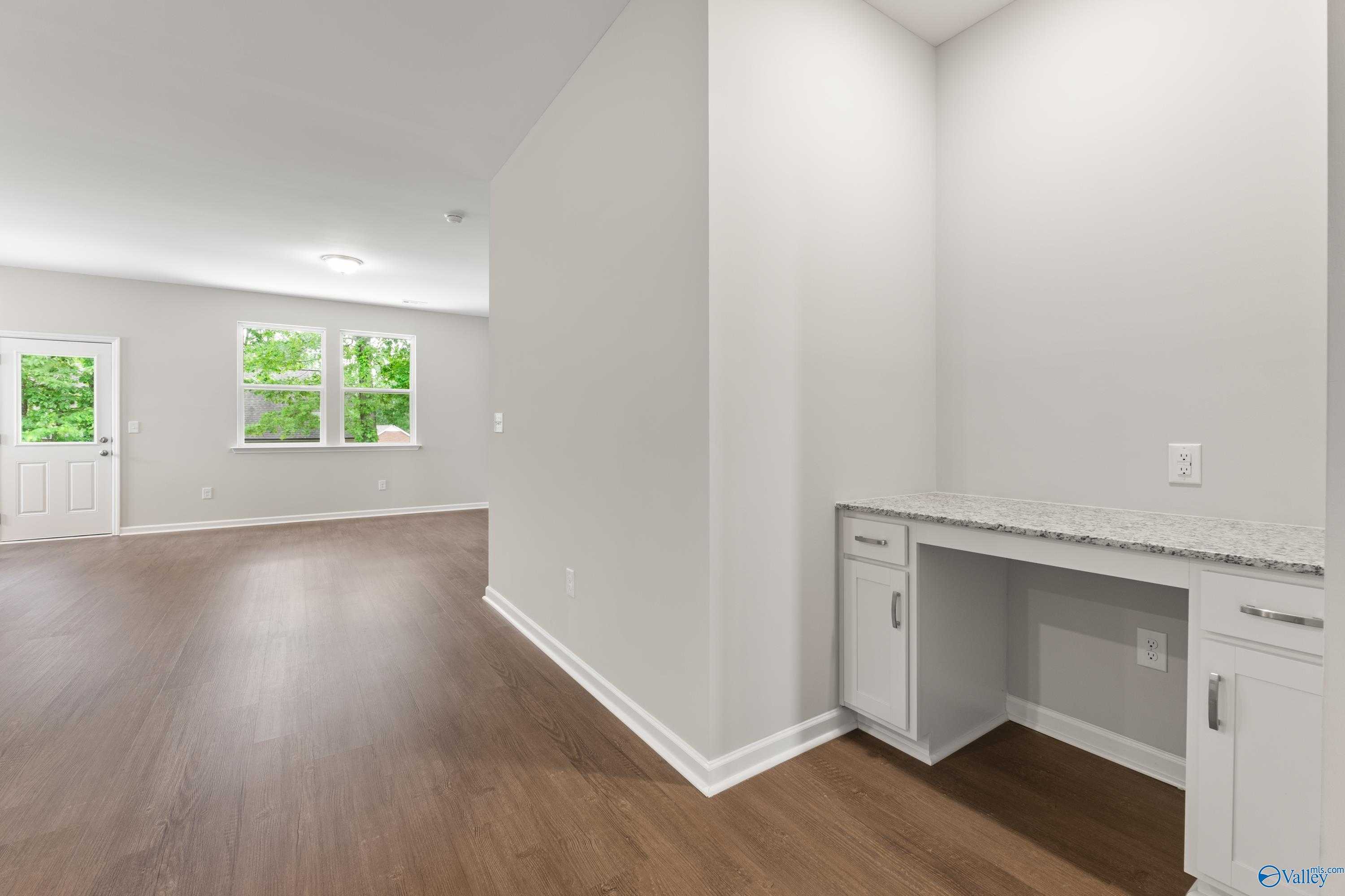 Modern built-in desk nook with white cabinets, granite countertop, and hardwood floors in Davidson Homes The Phoenix, Fayetteville, TN