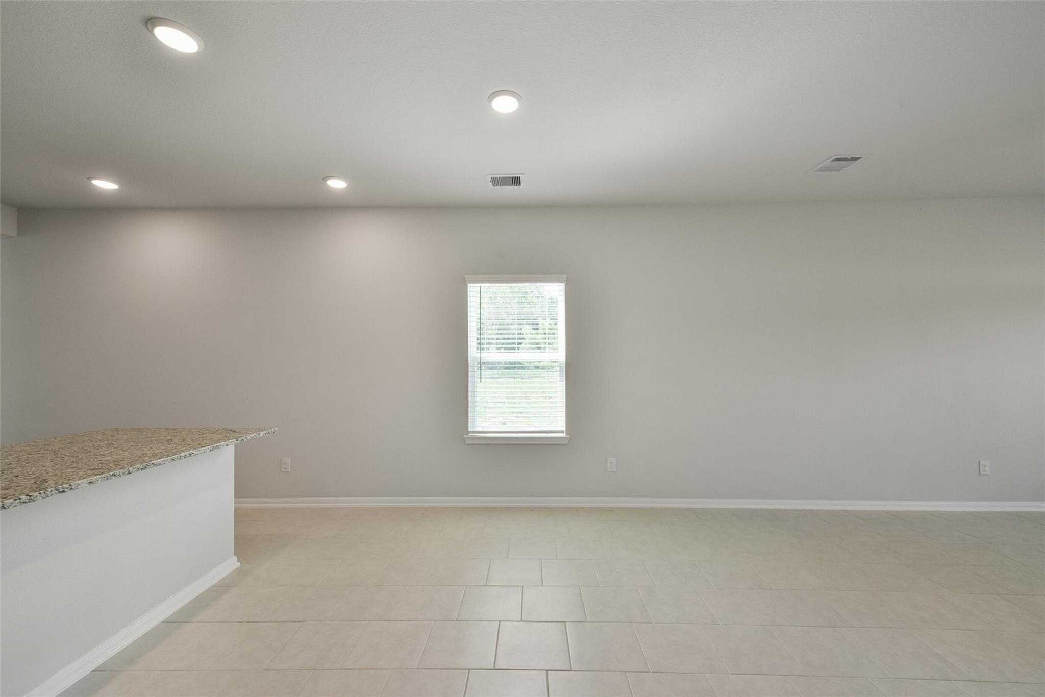 Bright open living space with white cabinets, beige countertop, tile floors, recessed lights, and window in The Sabine E home, Dayton Texas