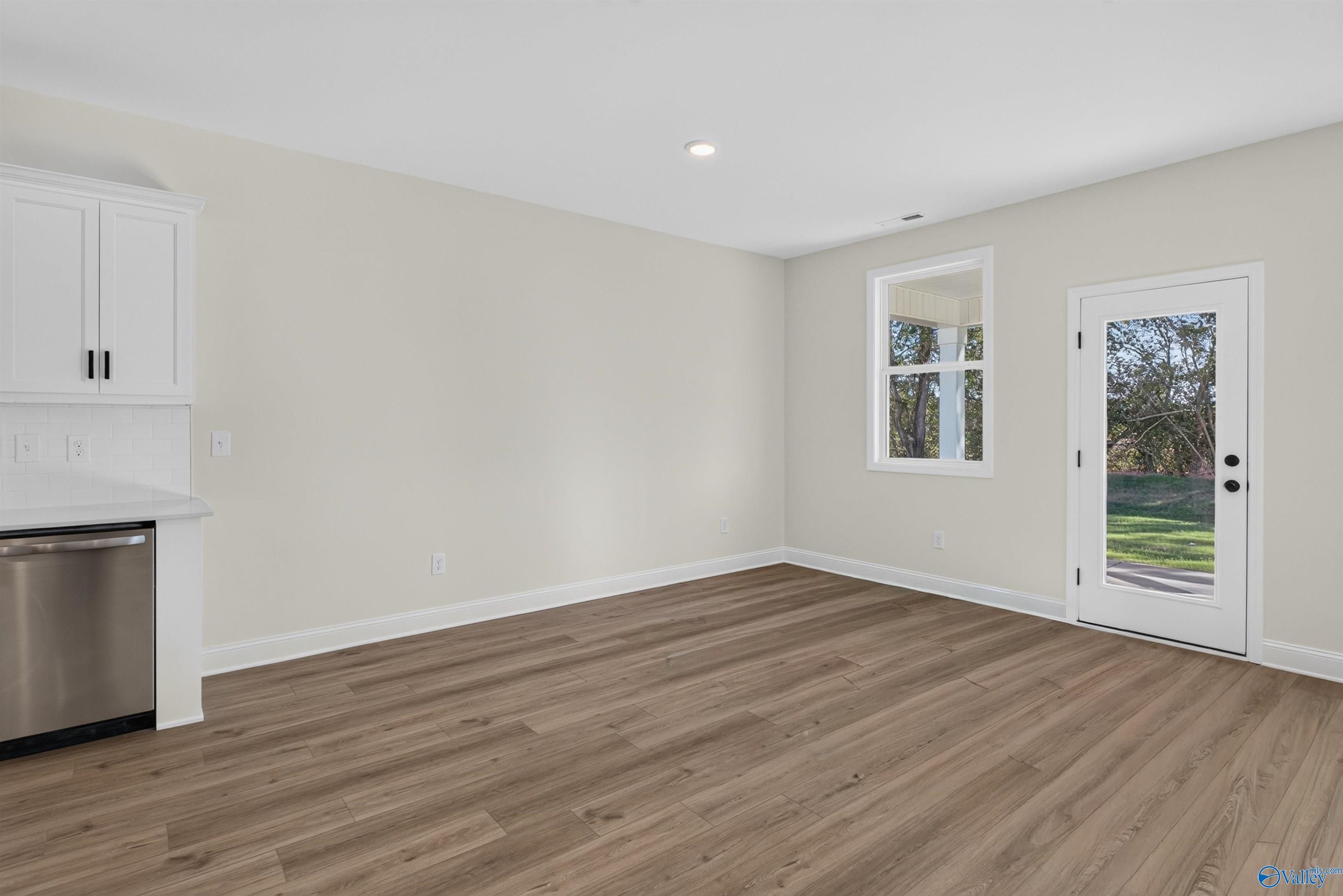 Open dining area with luxury vinyl plank flooring, white cabinetry, and glass back door in Davidson Homes Ashport L, New Market AL