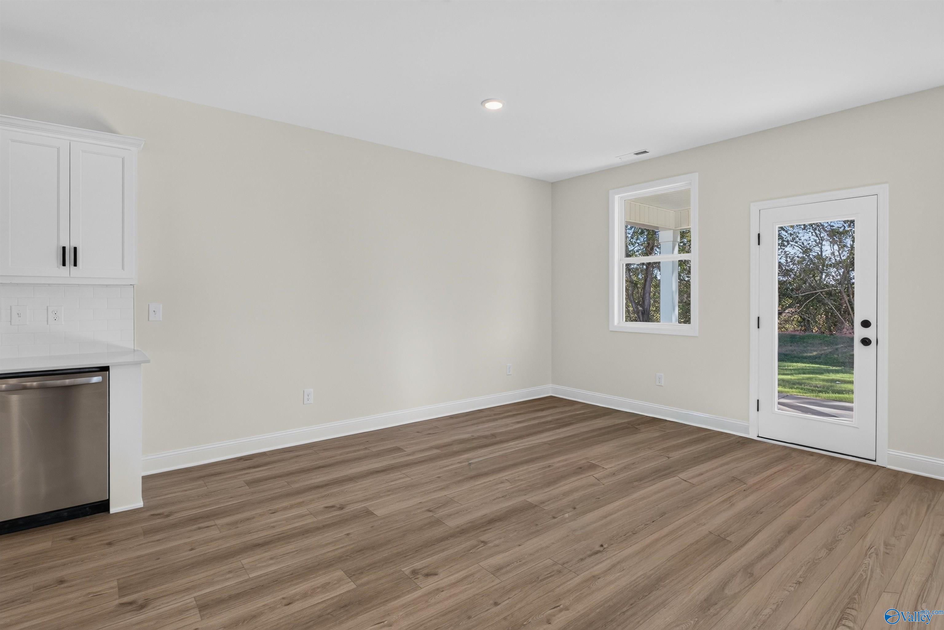 Open dining area with luxury vinyl plank flooring, white cabinetry, and glass back door in Davidson Homes Ashport L, New Market AL