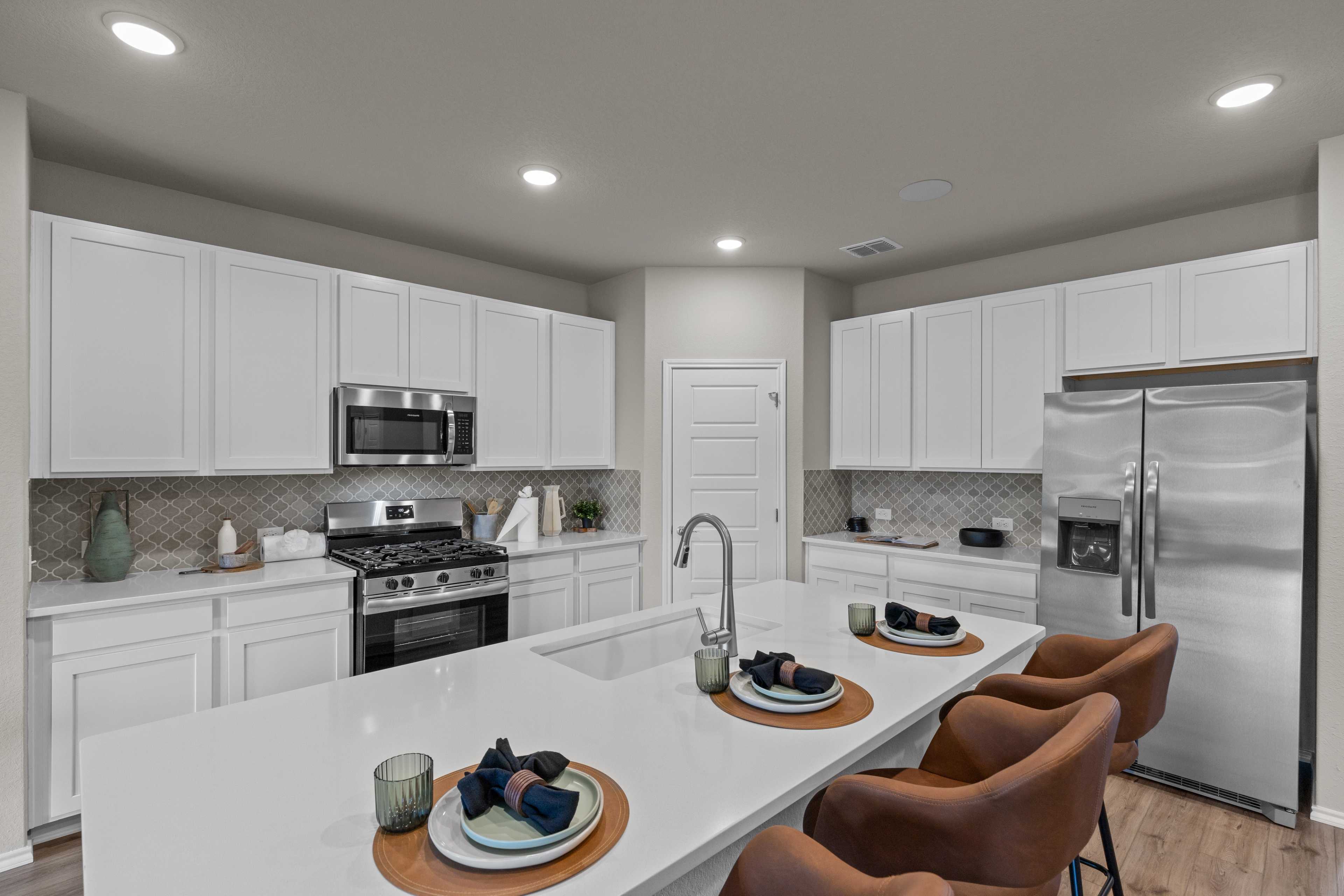 Spacious modern kitchen in Comanche Ridge San Antonio TX home by Davidson Homes featuring white cabinets, stainless appliances, and large island
