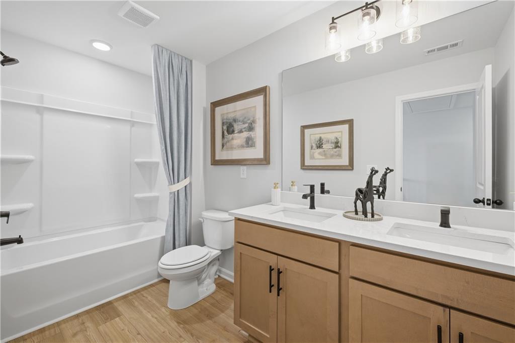 Bright bathroom with double vanity, white countertops, tub, and wood-look flooring in Davidson Homes The Sinclair B, Cartersville, GA