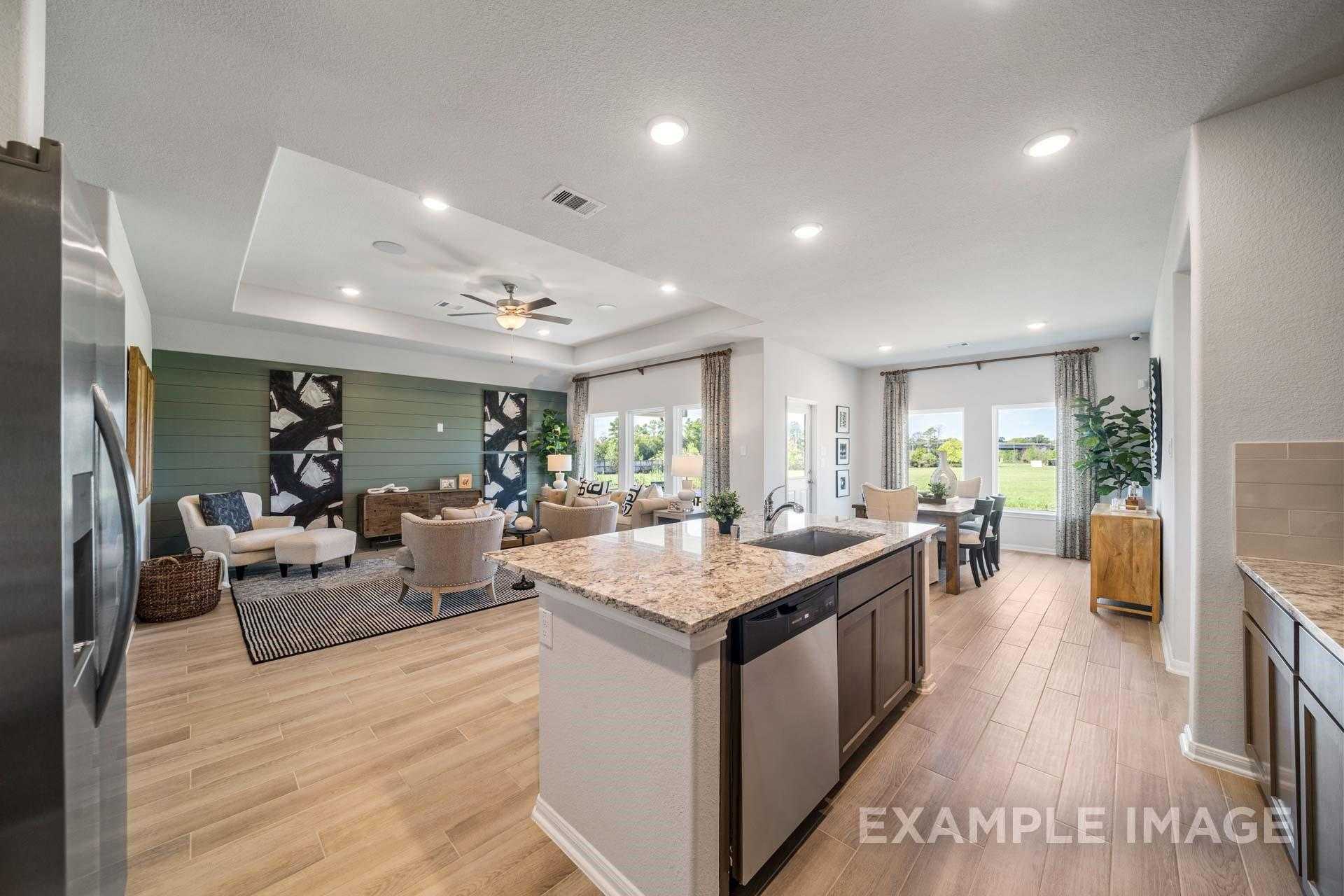 Open-concept living room and kitchen with granite island, stainless fridge in Davidson Homes The Acadia A, Lago Mar, Texas City