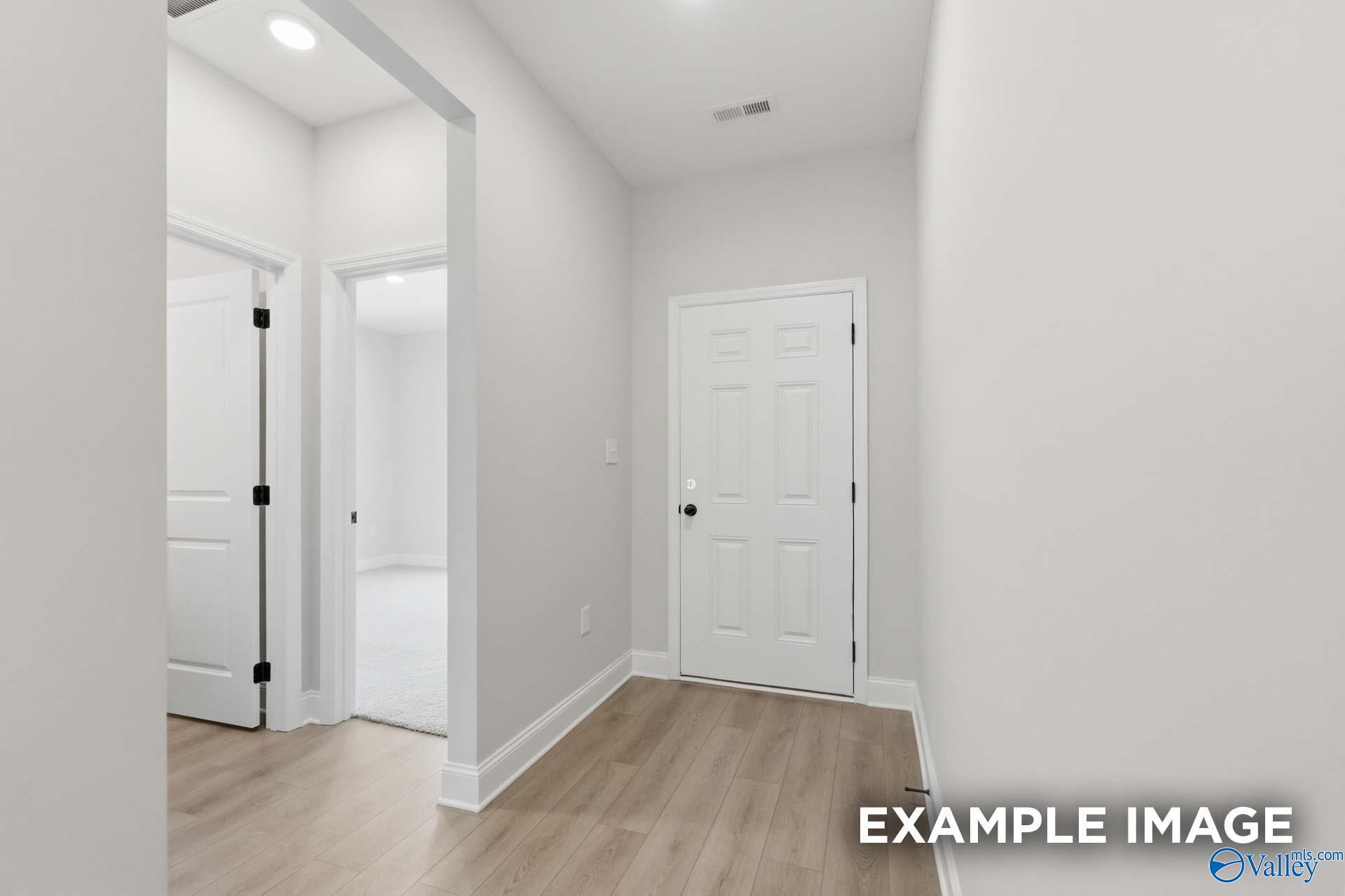 Bright entryway with modern wood-style flooring leading to interior doors in The Franklin C floor plan, Athens, Alabama.
