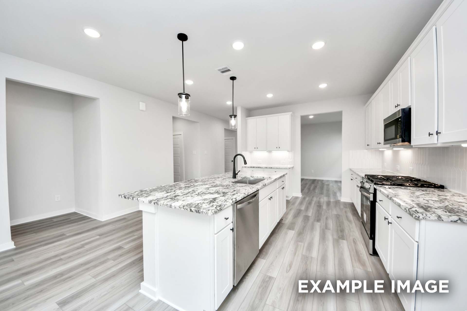 Modern kitchen in The Sorrento featuring white cabinets, granite countertops, and a spacious island in Crosby, Texas.