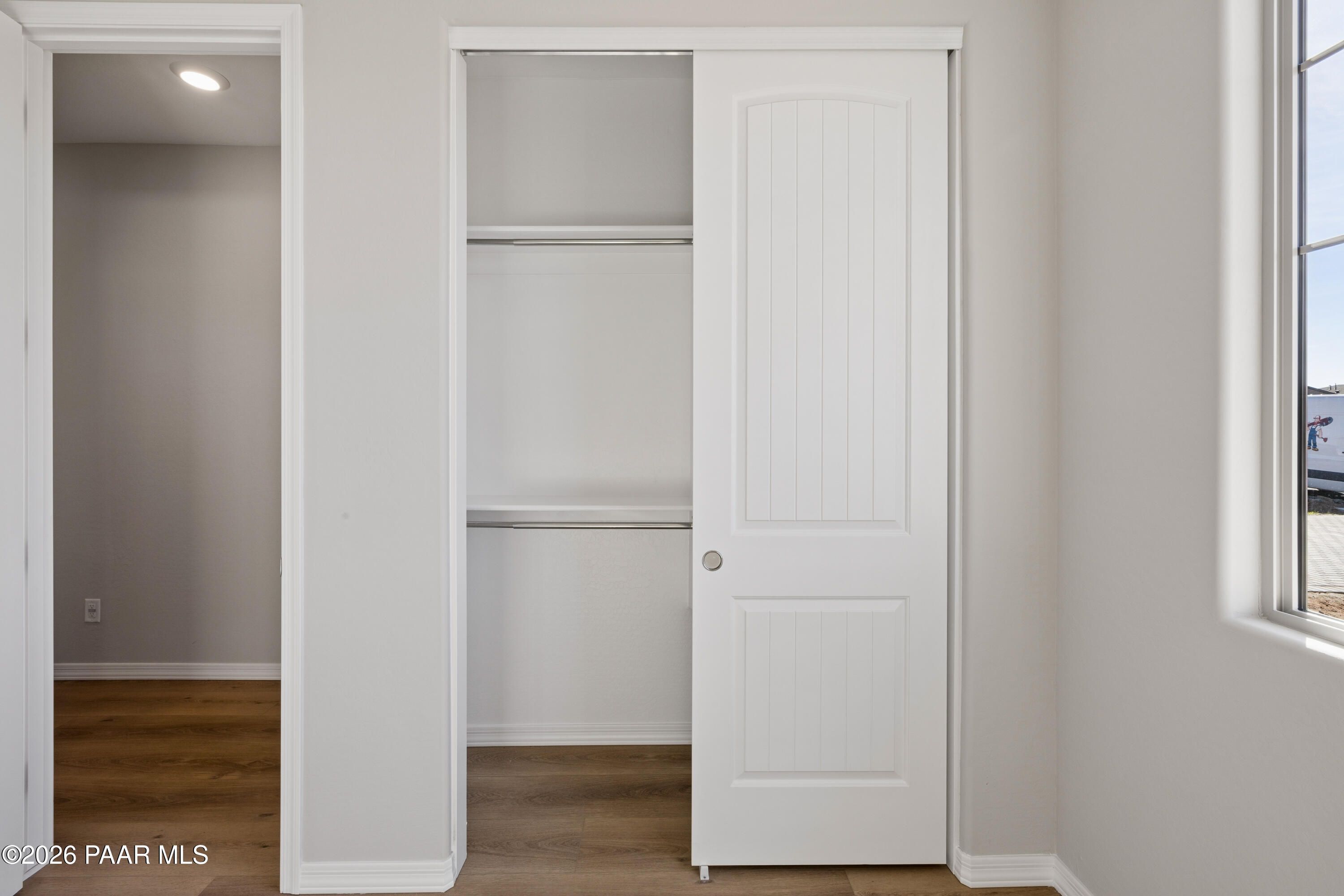 Spacious walk-in closet with white sliding doors, shelves, and rod in bedroom of Davidson Homes The Harmony A, Prescott Valley, AZ