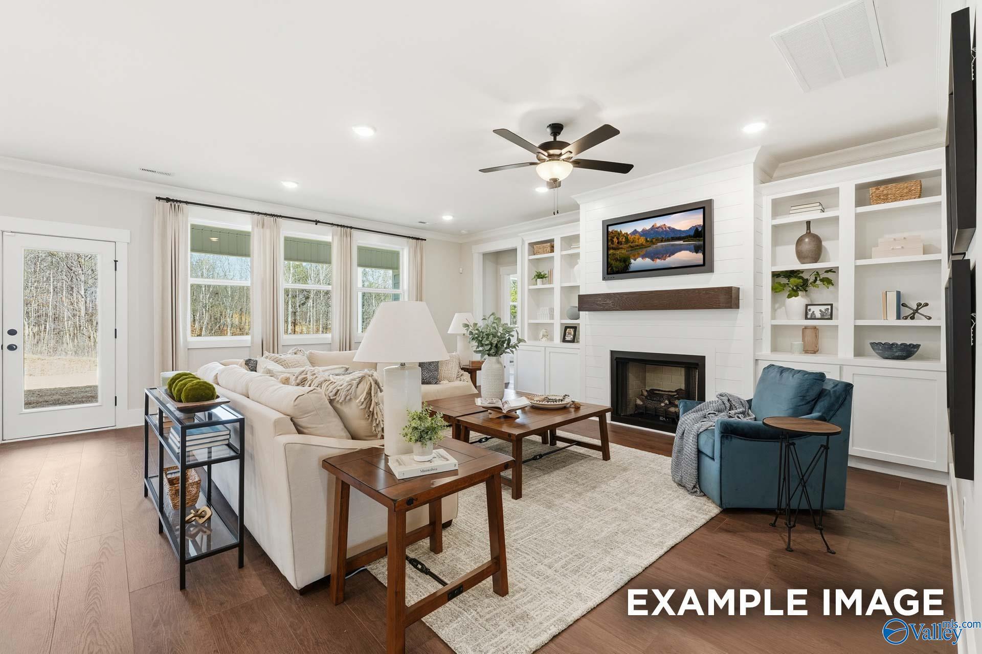 Bright great room with fireplace, built-in shelving, and hardwood floors in The Hibiscus F by Davidson Homes, Arab, Alabama