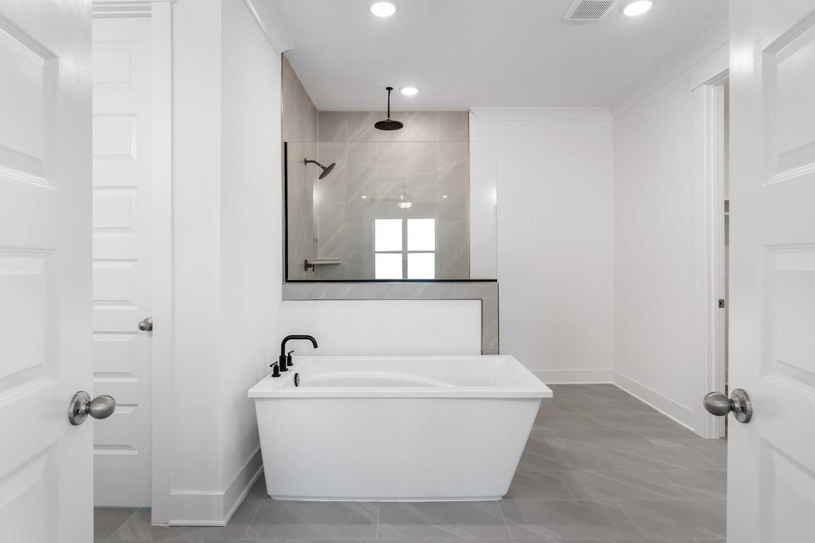 Elegant master bathroom with freestanding white tub, black faucet, and glass shower in Davidson Homes The Hathaway, Murfreesboro, TN