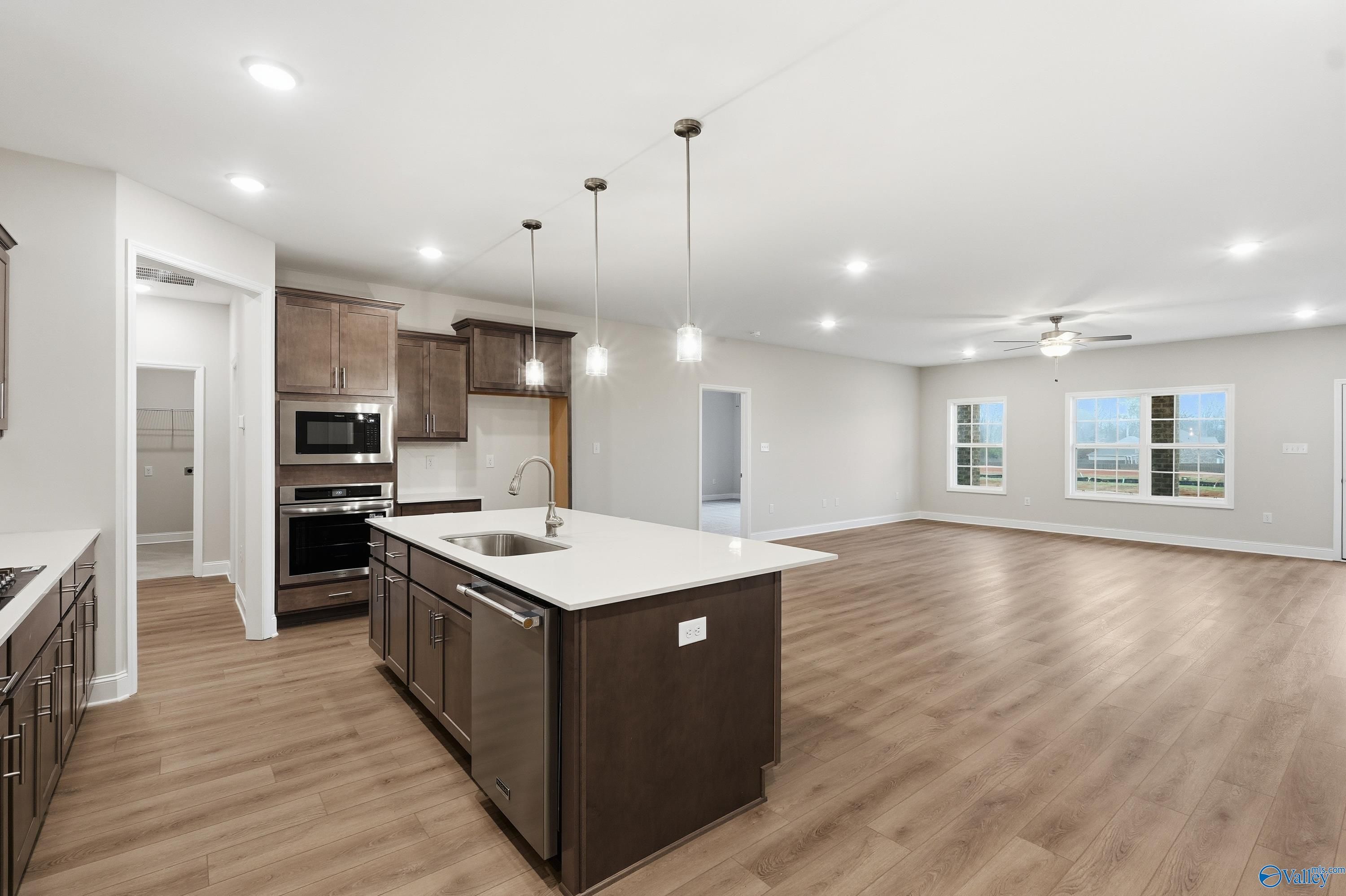 Modern open-concept kitchen with quartz island, stainless appliances, and hardwood floors in The Kirkland 3-bedroom home, Decatur, Alabama