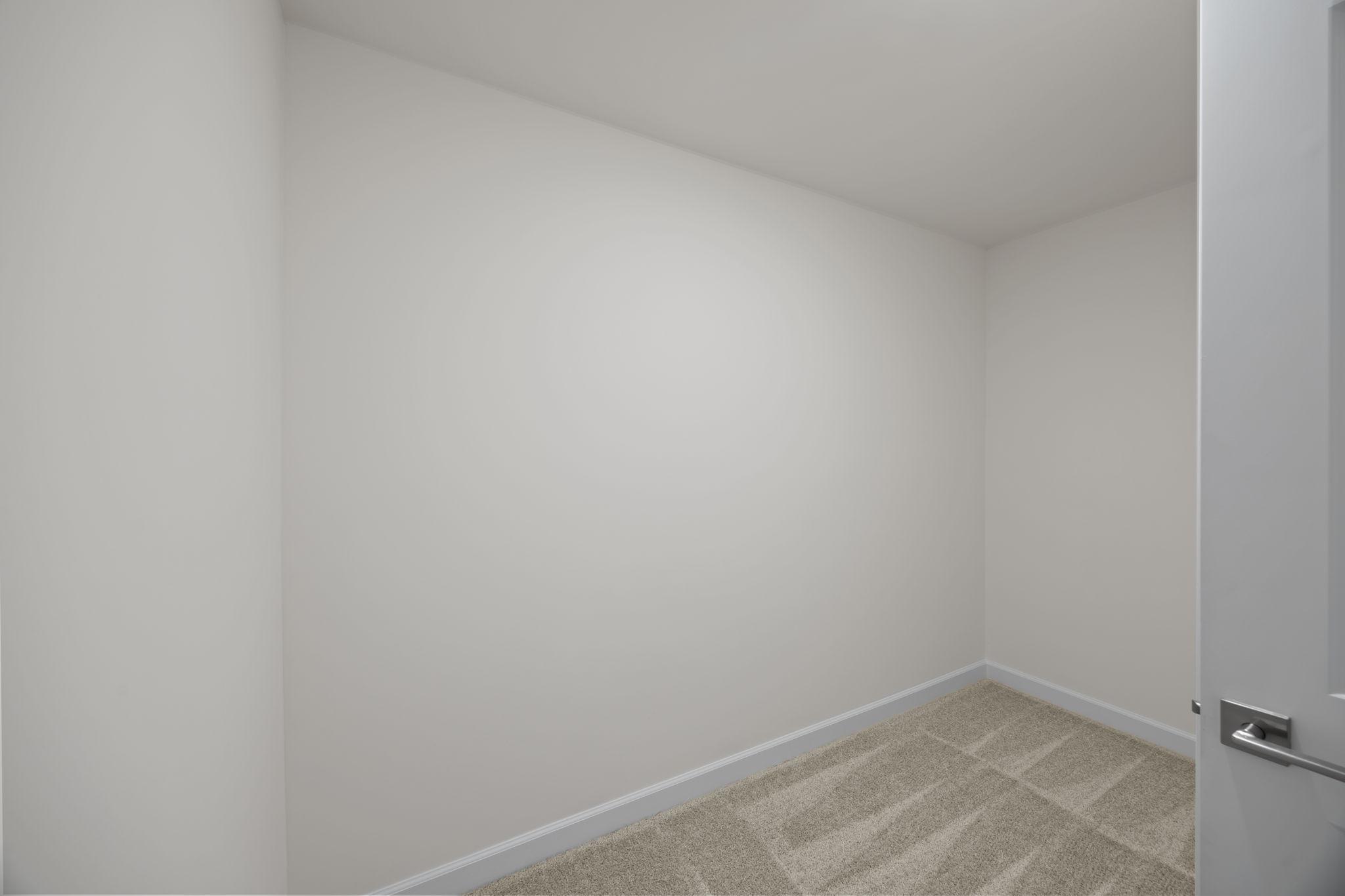 Spacious walk-in closet with neutral carpet and white walls in a Davidson Homes floor plan at Springvale South, Fuquay-Varina.
