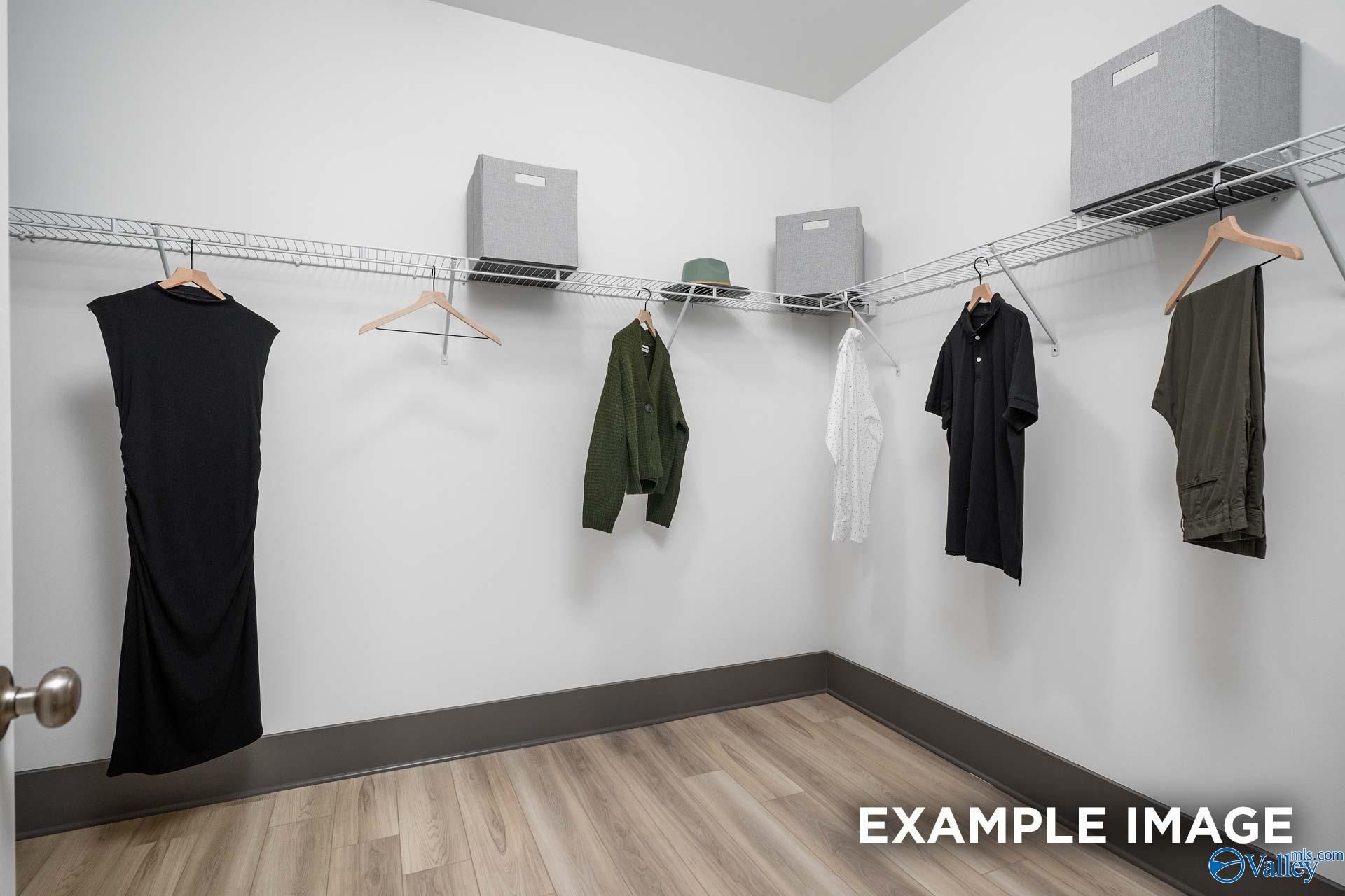 Spacious walk-in closet with wire shelving, gray bins, hanging clothes and hat in Davidson Homes Rockford B, Madison Alabama