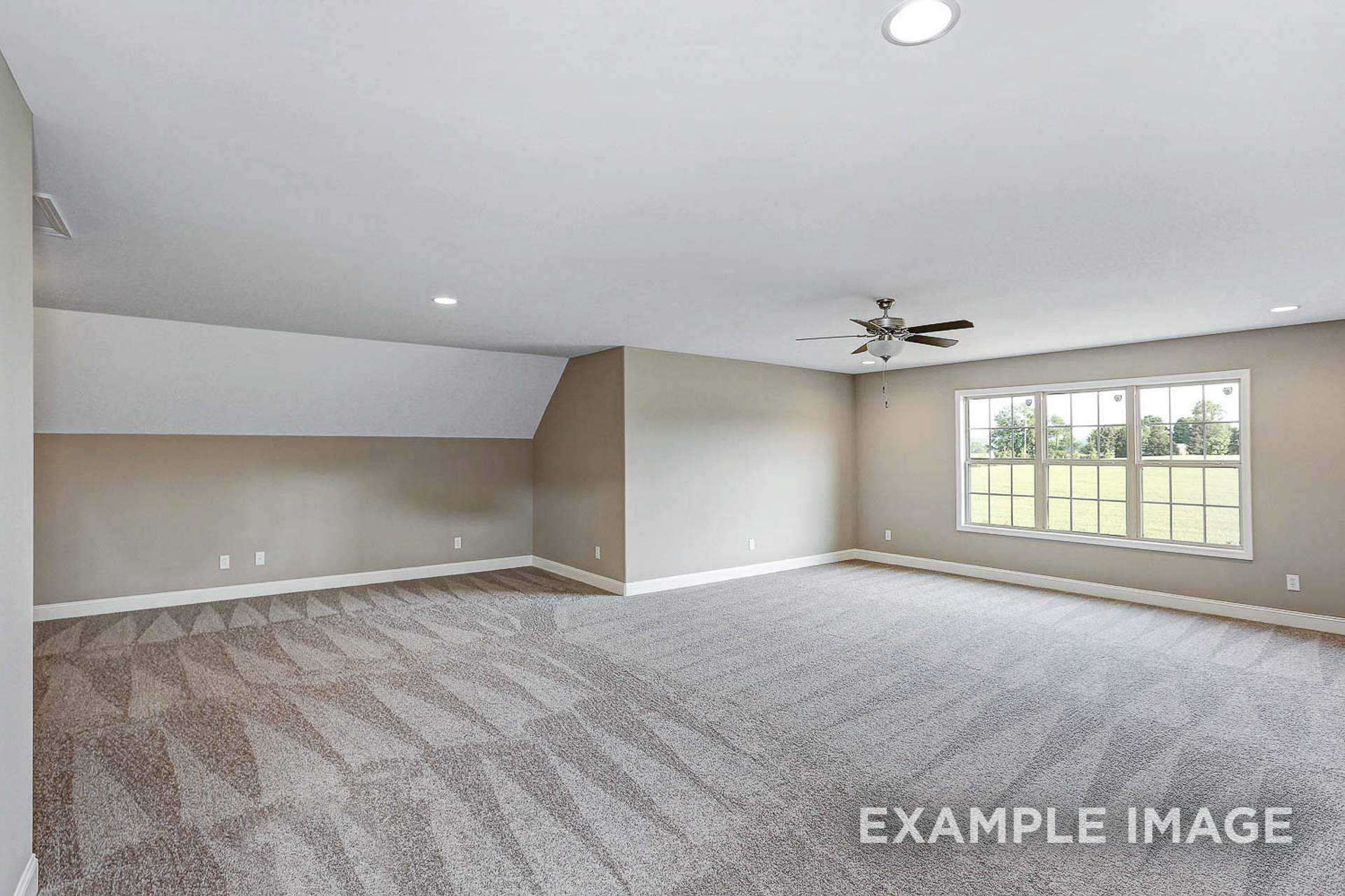 Spacious bonus room in The Montgomery B featuring sloped ceiling, beige walls, carpeted floor, ceiling fan, and large windows overlooking fields