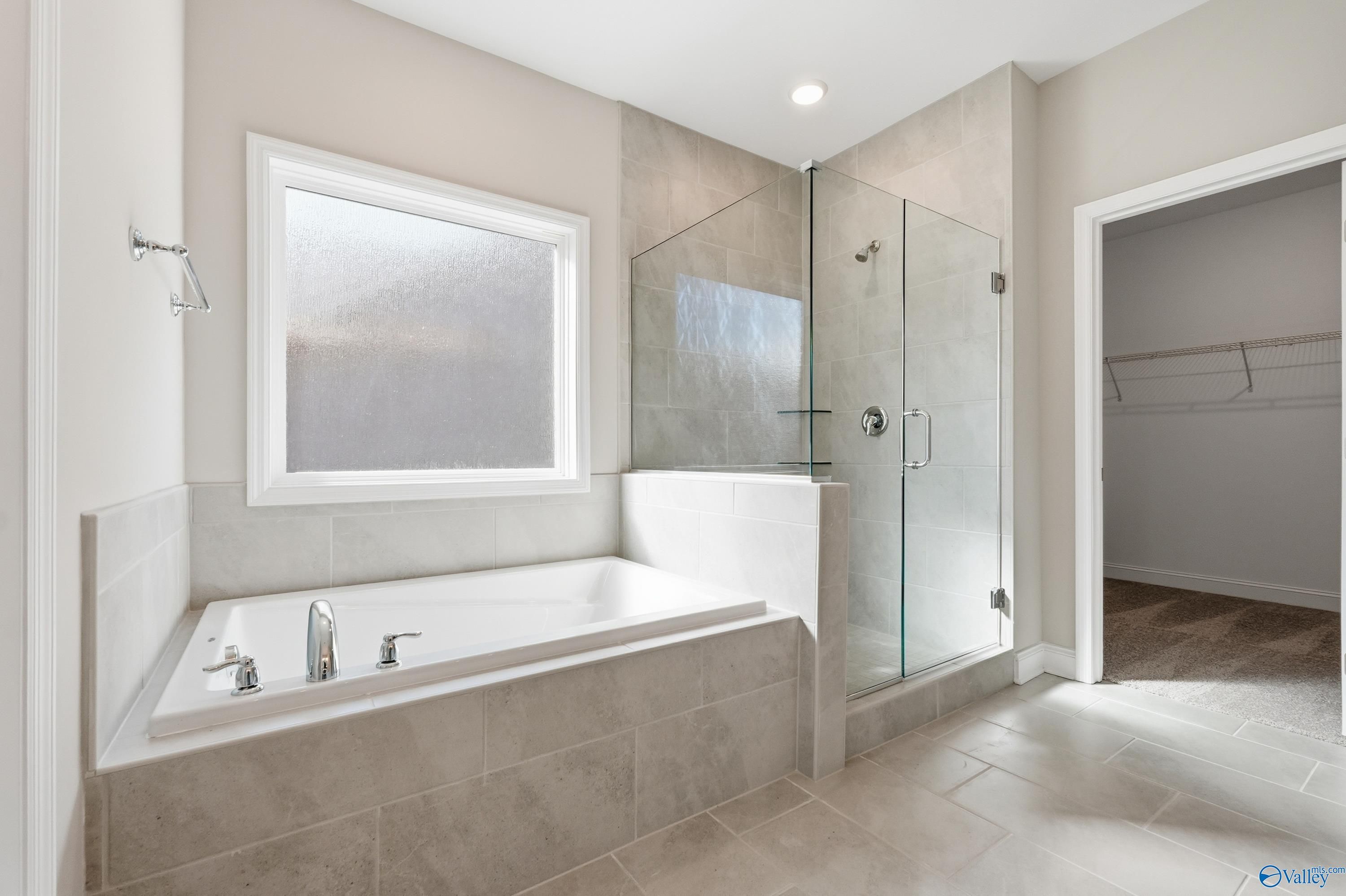 Modern master bathroom with glass shower, freestanding tub, and frosted window in Davidson Homes The Rockford, Harvest, AL