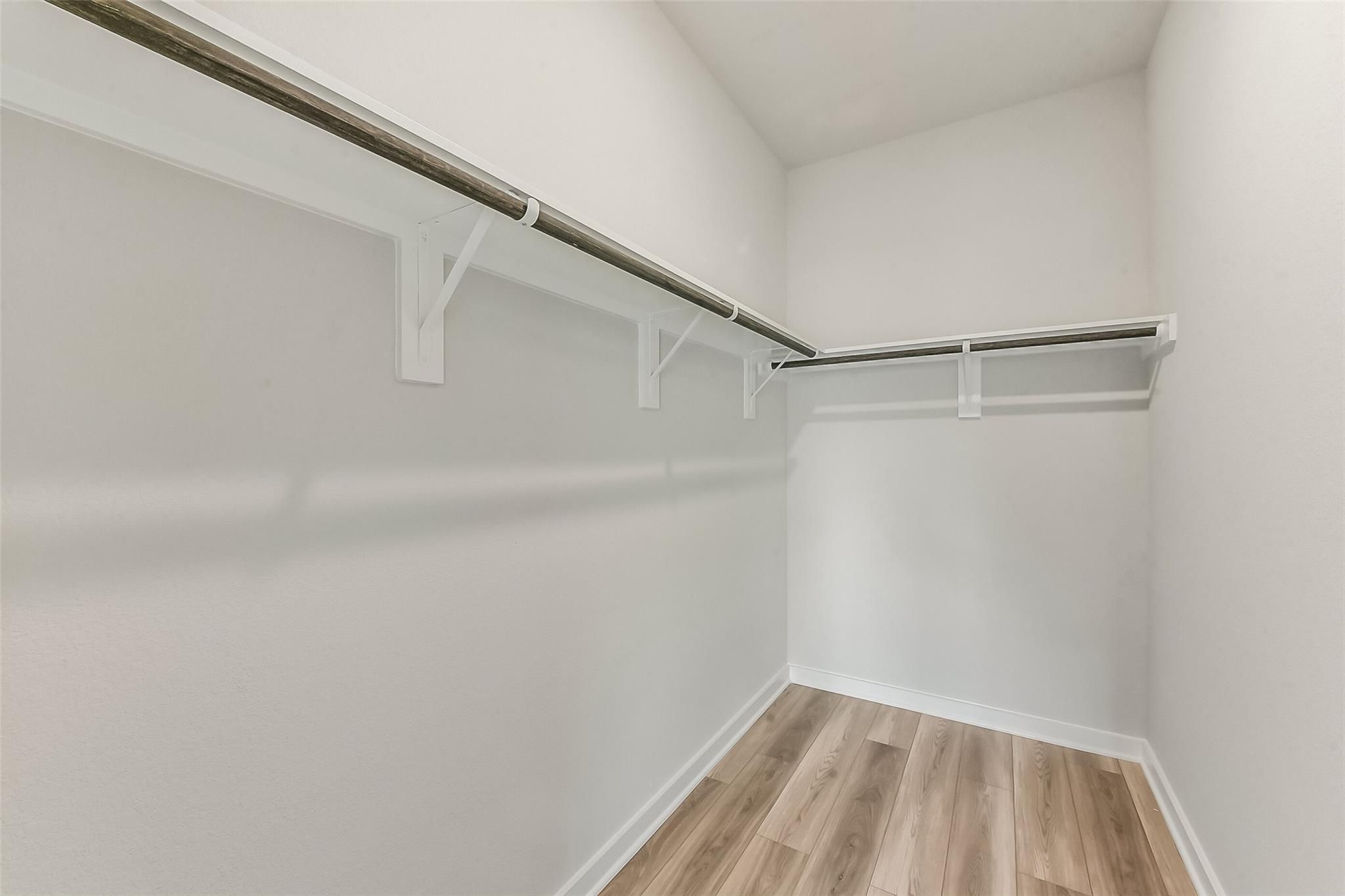 Spacious walk-in closet with wooden shelves and hanging rods in Davidson Homes The Frio G, Windmill Estates, Magnolia, Texas