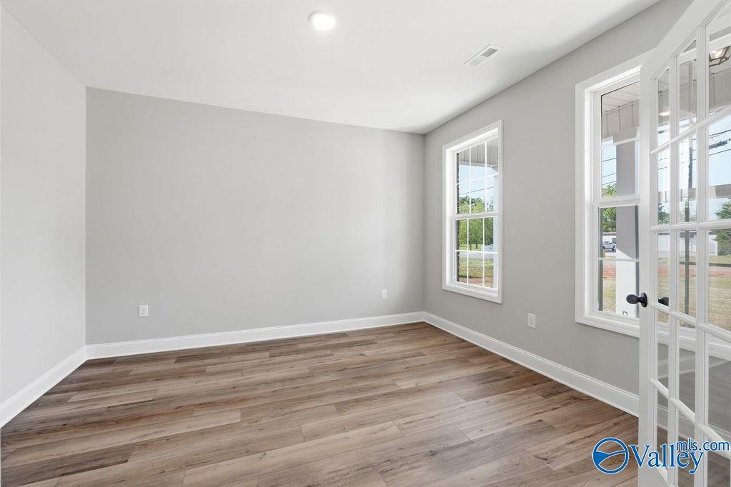 Bright empty room with gray walls, hardwood floors, large windows and French doors in Davidson Homes The Emory, Decatur, Alabama