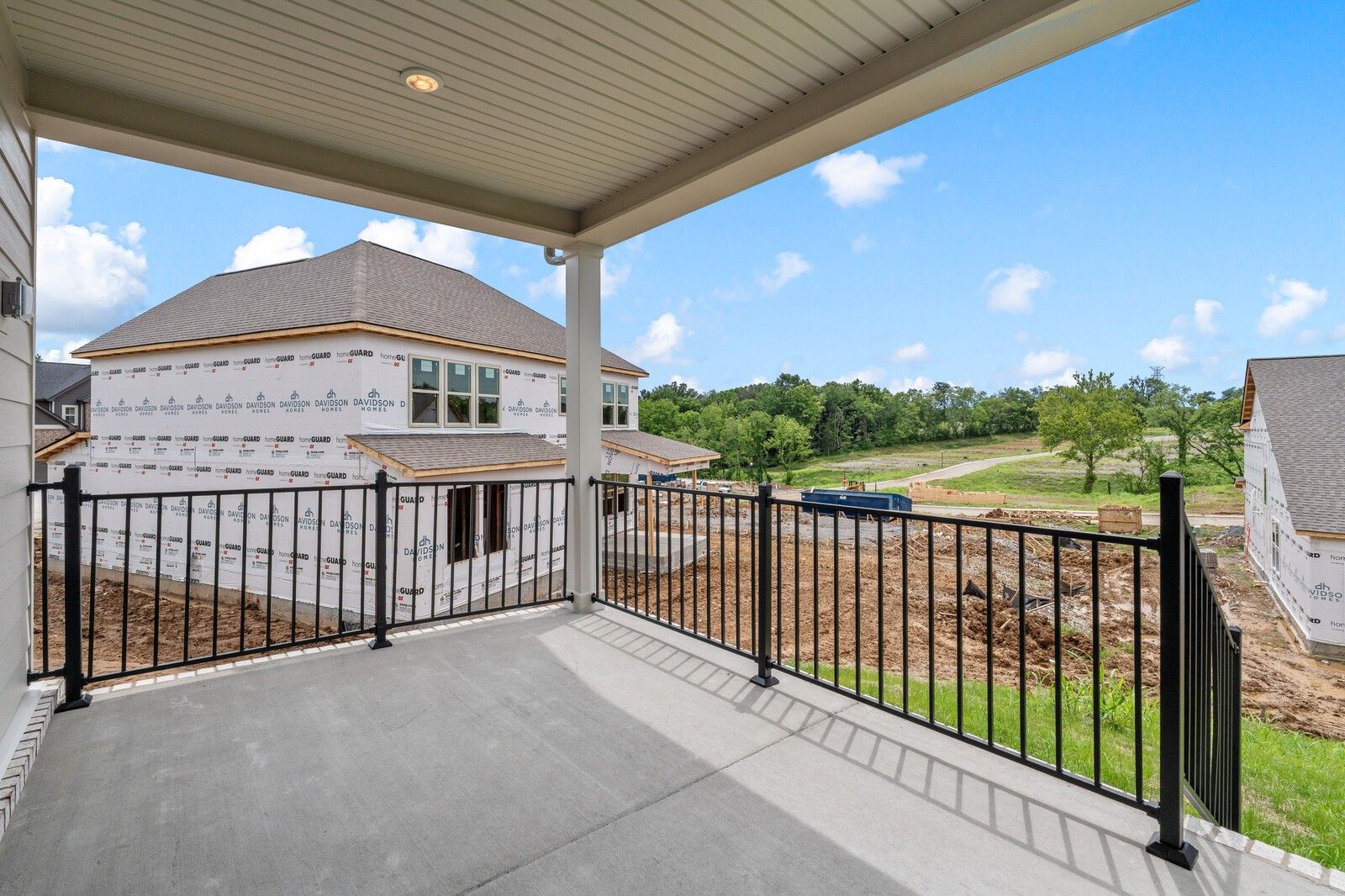 Covered patio with metal railing overlooking new home construction in Woods Crossing, Gallatin, Tennessee by Davidson Homes.