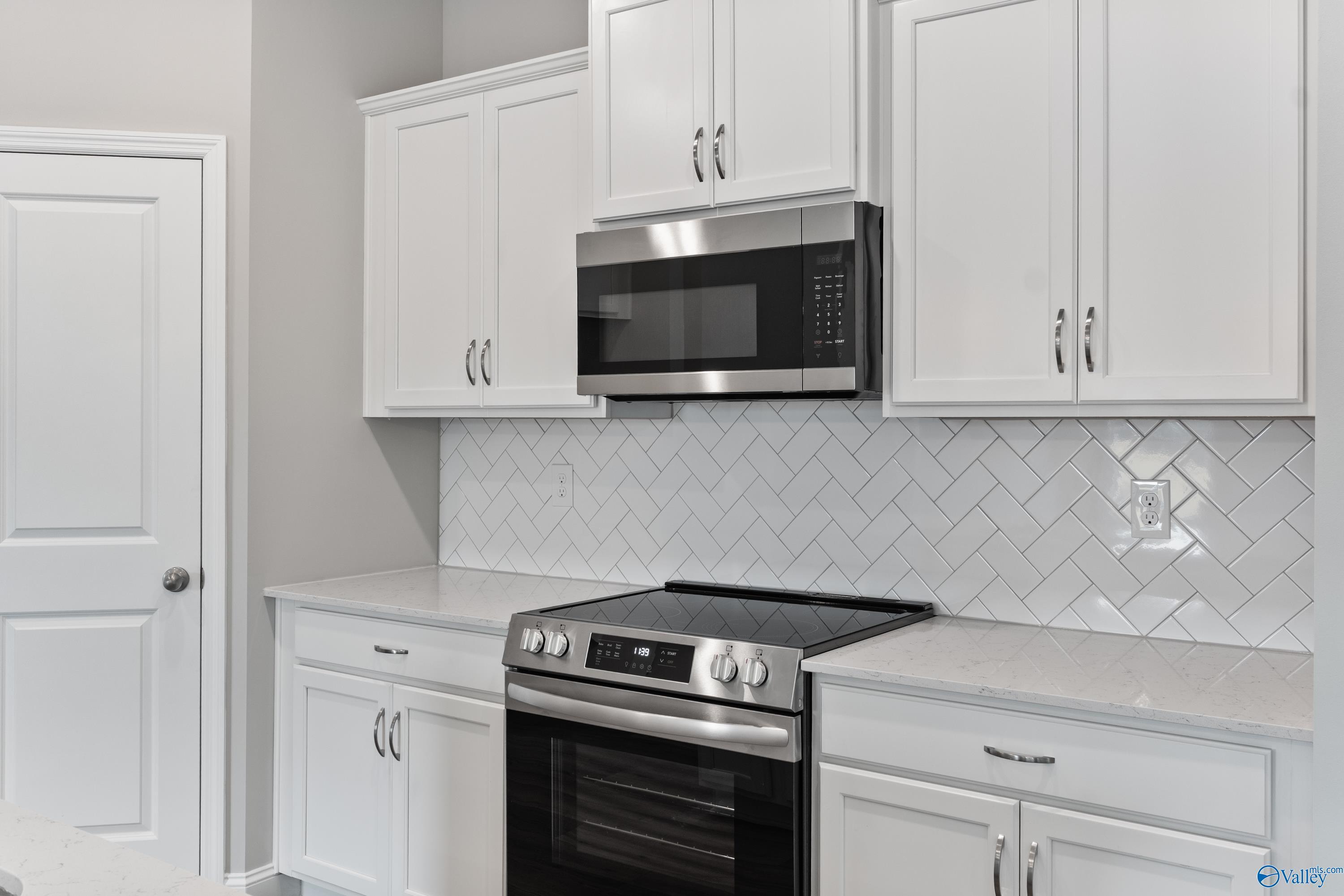 Modern white shaker kitchen with stainless appliances, herringbone subway tile backsplash in Davidson Homes The Franklin, Huntsville AL
