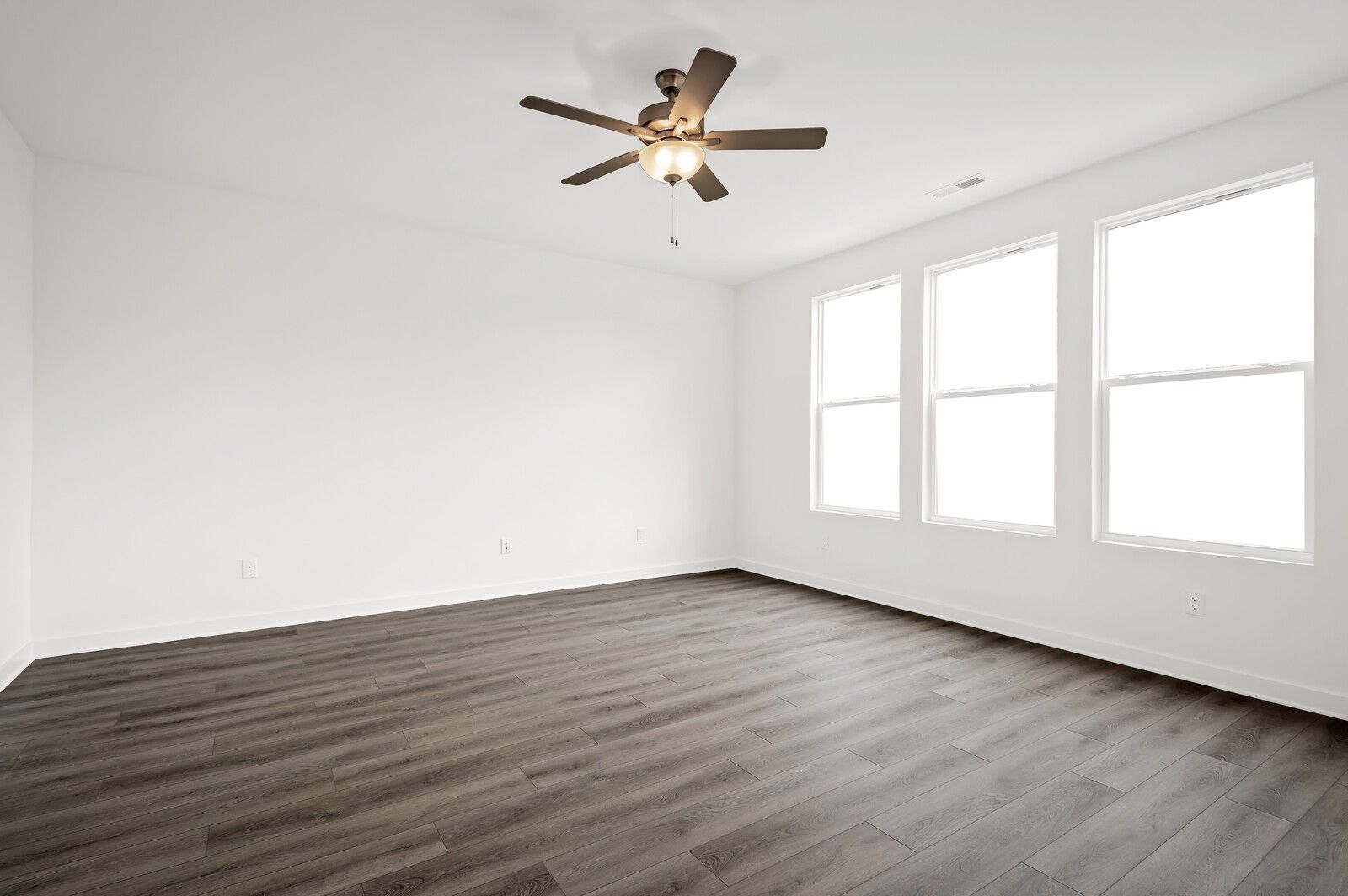 Bright, spacious bedroom with wood-look flooring and ceiling fan in The Logan C floor plan at Calista Farms, White House.