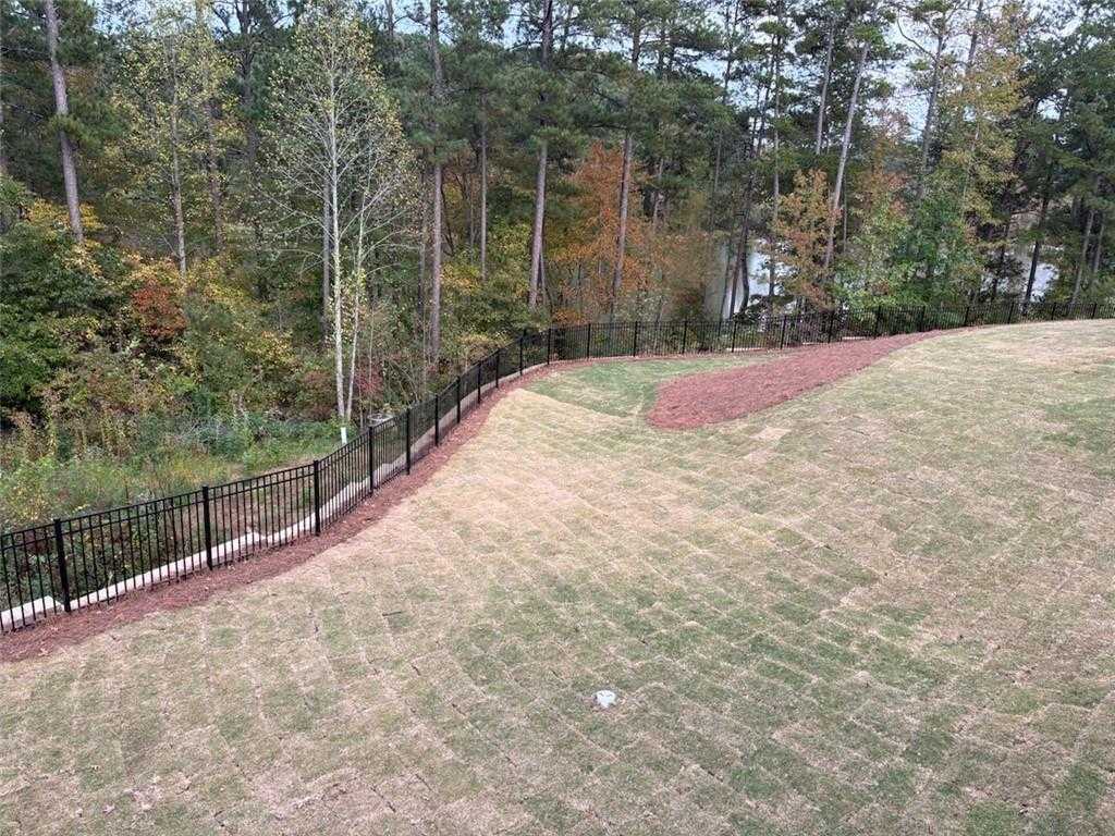 Private fenced backyard with new sod overlooking autumn woods and lake in Riverwood, Dallas, Georgia 6-bedroom home