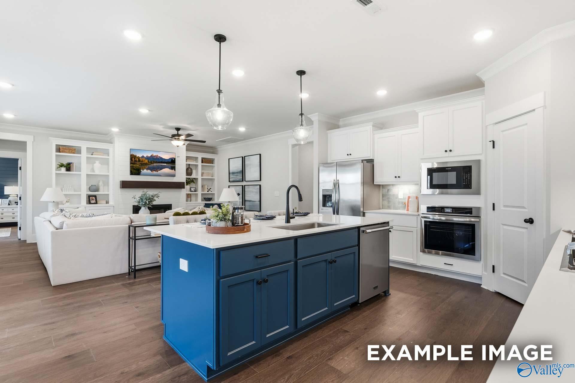 Open-concept kitchen with navy island, white cabinetry, and stainless appliances in Davidson Homes The Hibiscus F, Arab, Alabama