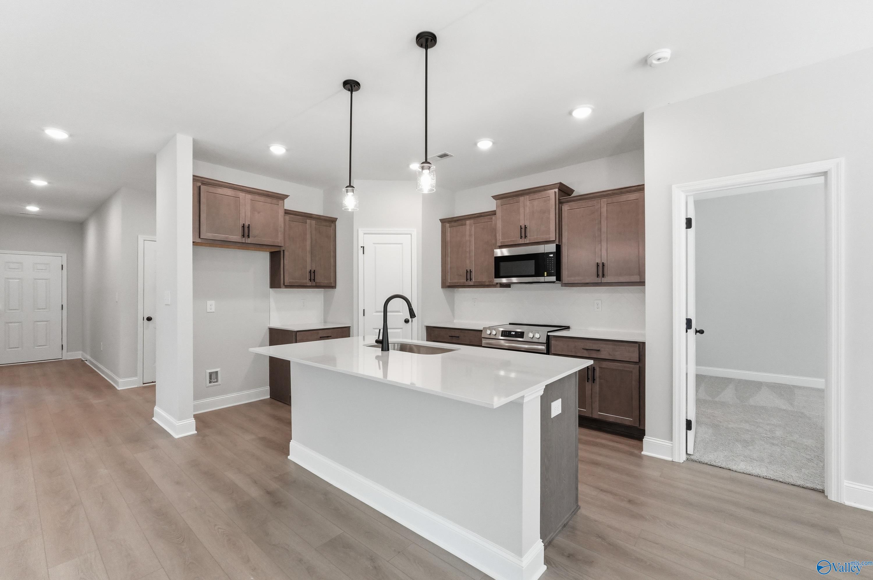 Modern kitchen featuring white quartz island, shaker brown cabinets, stainless appliances in Davidson Homes The Franklin, Huntsville AL