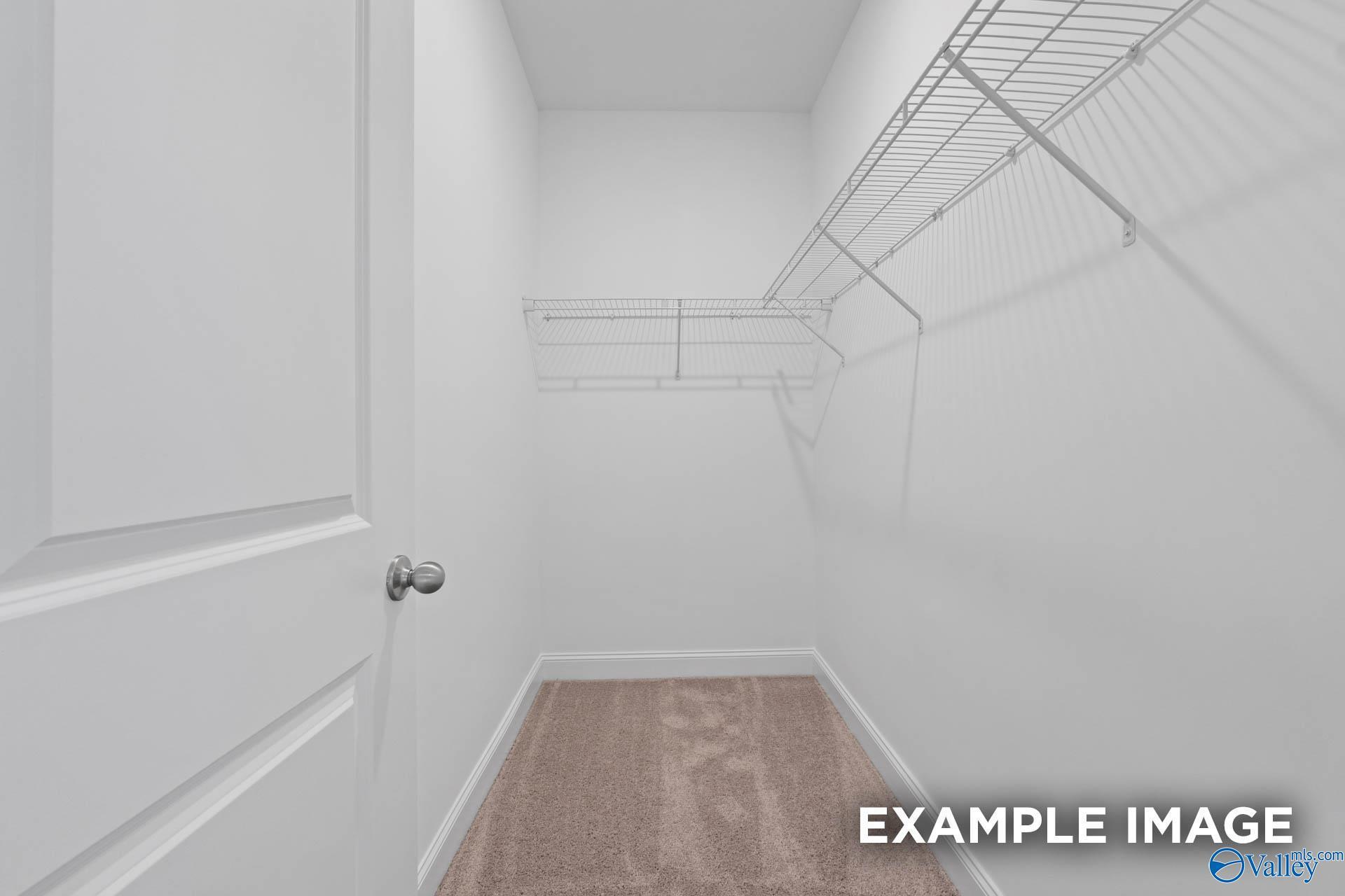 Spacious walk-in closet with wire shelving and white walls in Davidson Homes The Butler 3-bedroom home, Owens Cross Roads, Alabama