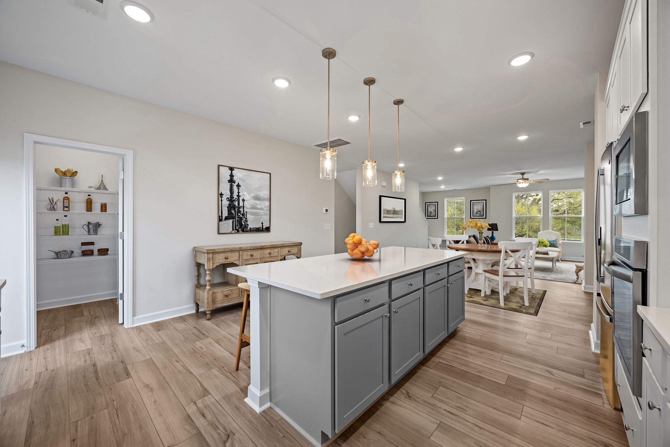 Open-concept kitchen in The Avery featuring a center island, pendant lighting, and a walk-in pantry in Knightdale, NC.