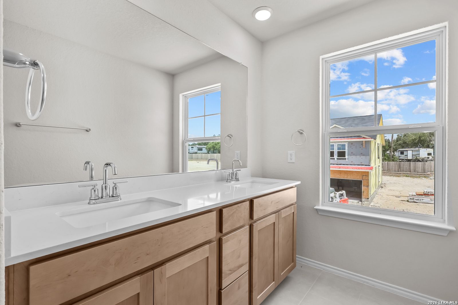 Modern bathroom with double vanity and large mirror in The Gillian B floor plan at Meadows at Oak Creek, San Antonio, Texas.