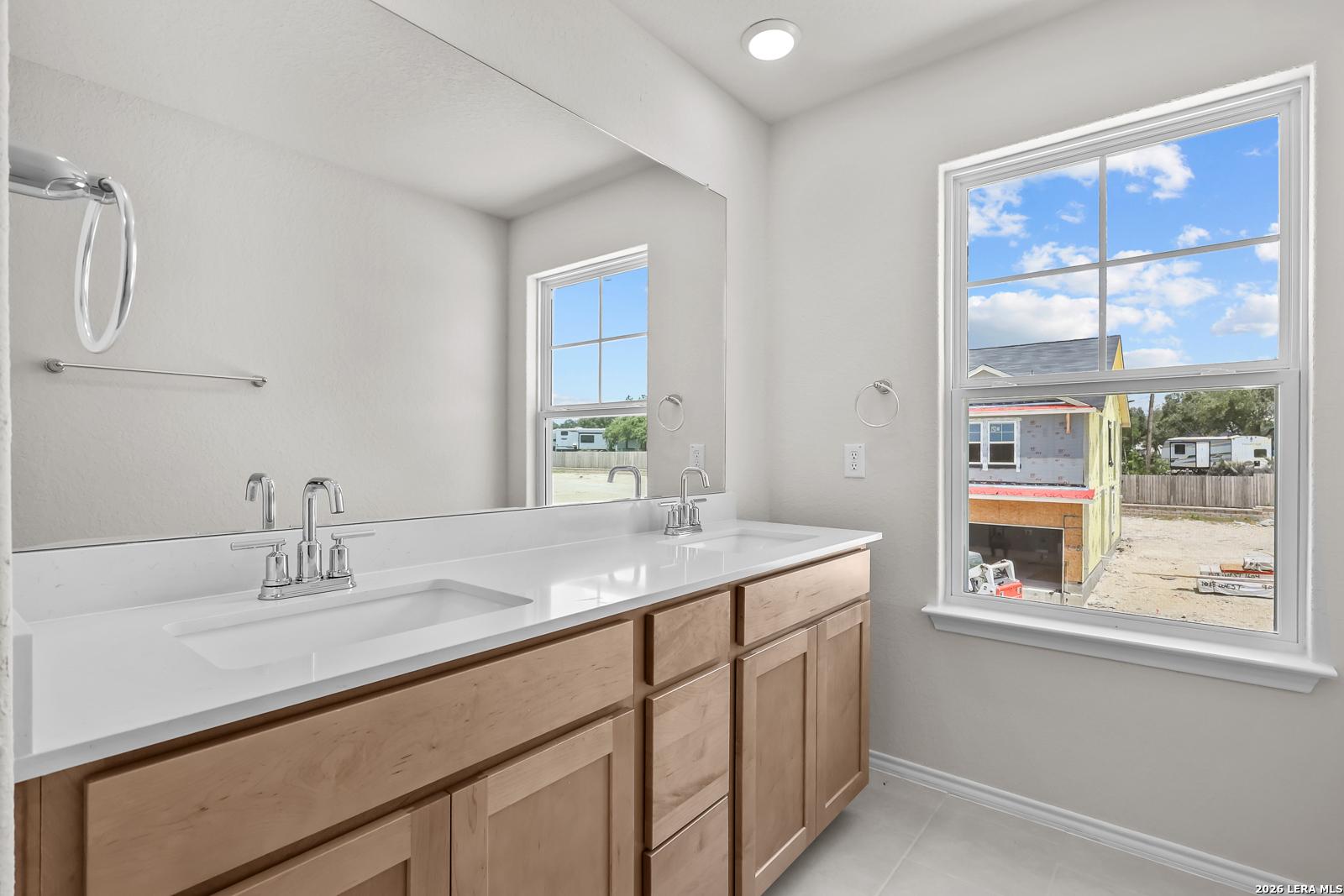 Modern bathroom with double vanity and large mirror in The Gillian B floor plan at Meadows at Oak Creek, San Antonio, Texas.