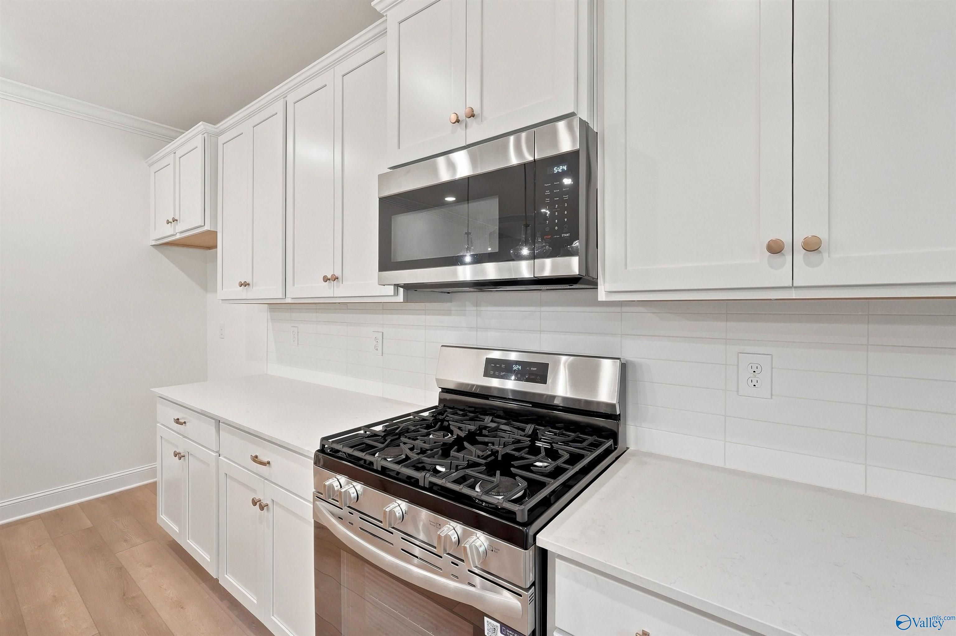 Modern kitchen with white shaker cabinets, gas range, and quartz countertops in The Chelsea C home at Creek Grove, Alabama.