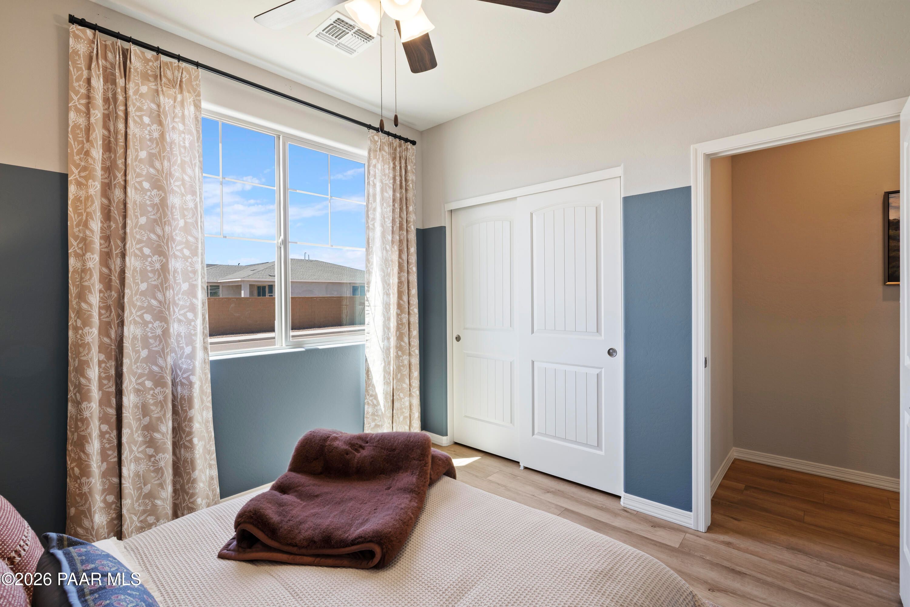 Bright bedroom with blue accent wall, sliding closet, and large window in The Harmony A plan at Pronghorn Ranch, Prescott.