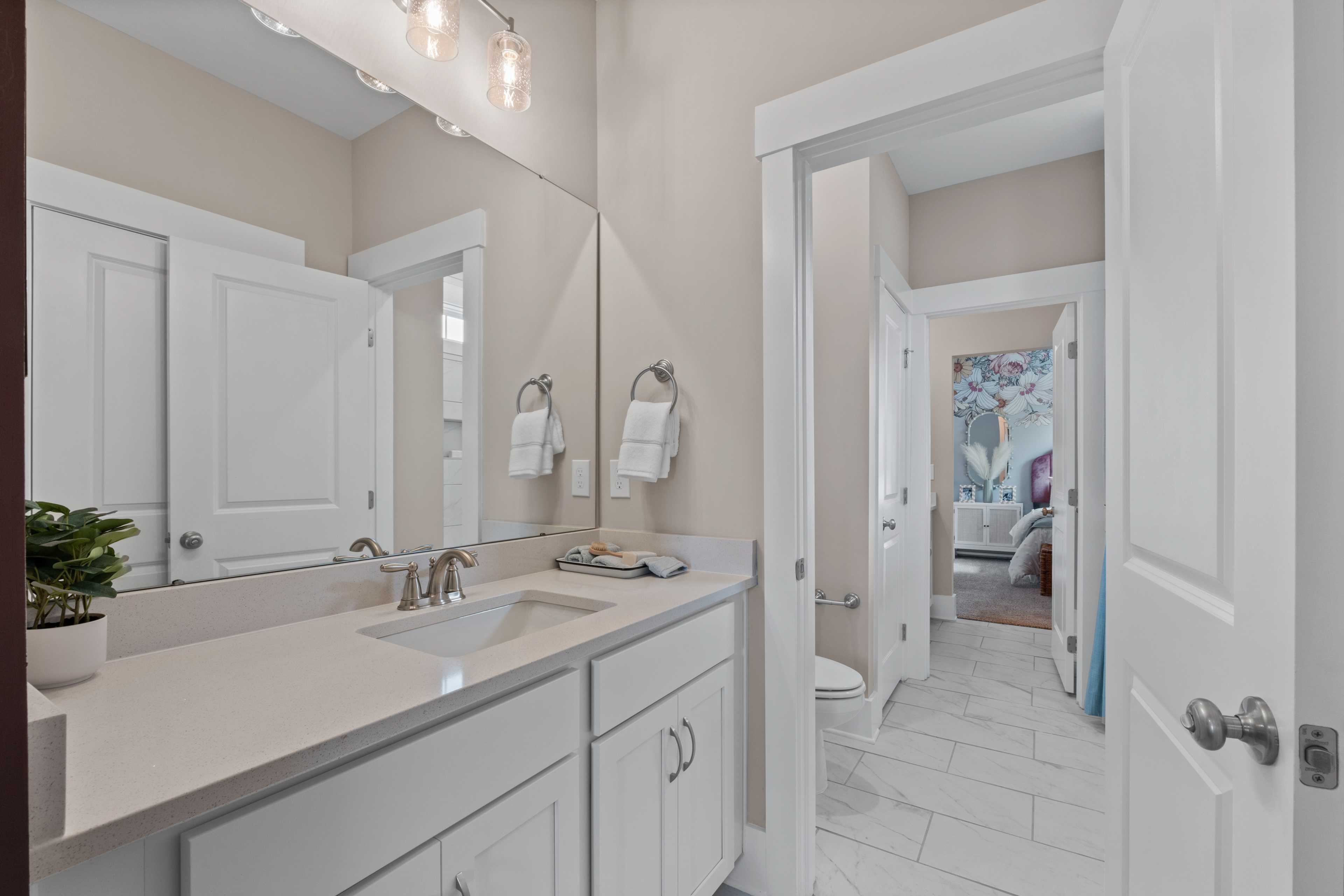 Spacious primary bathroom in Creekside, Harvest AL with white shaker vanity, quartz countertop, and open bedroom view