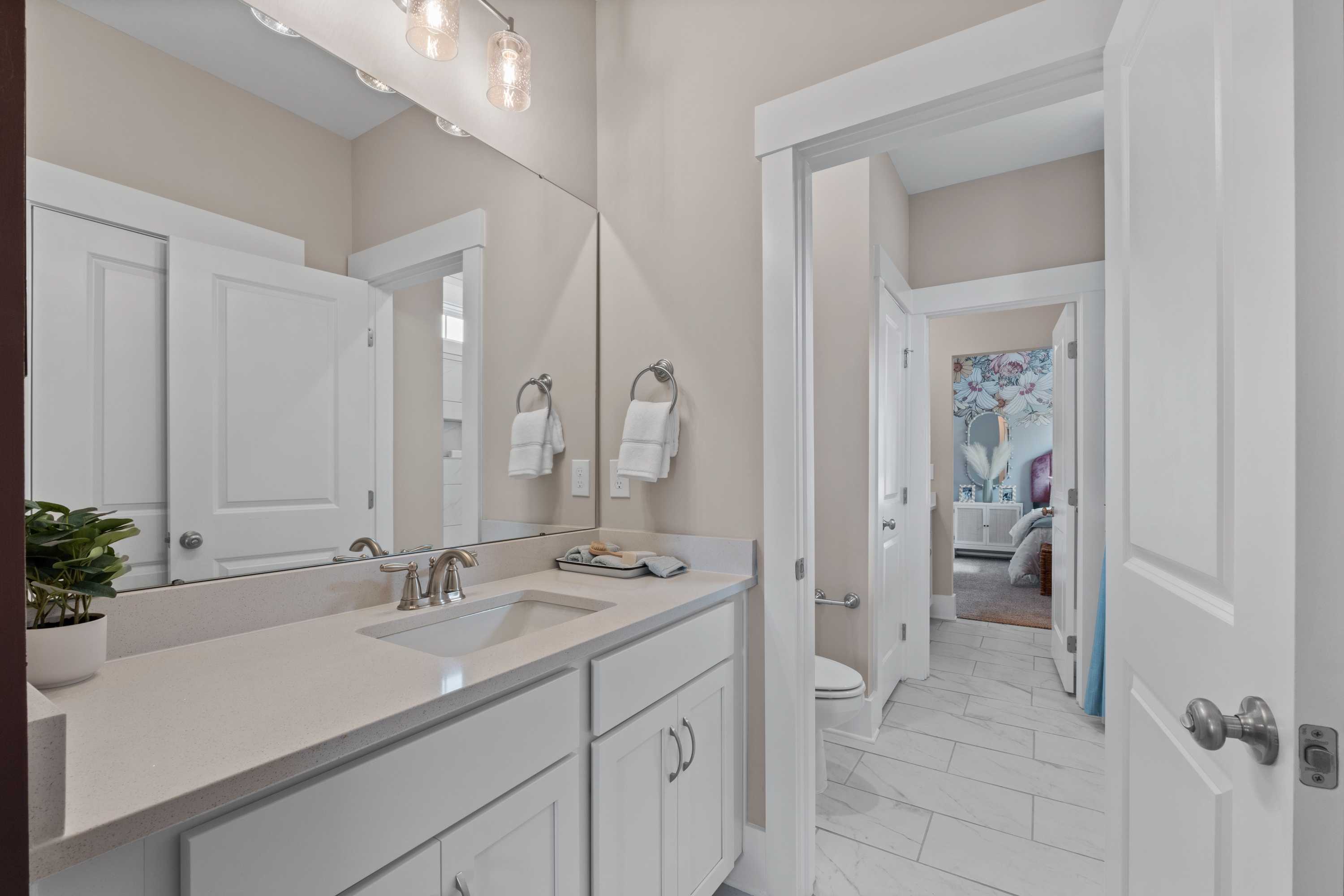 Spacious primary bathroom in Creekside, Harvest AL with white shaker vanity, quartz countertop, and open bedroom view
