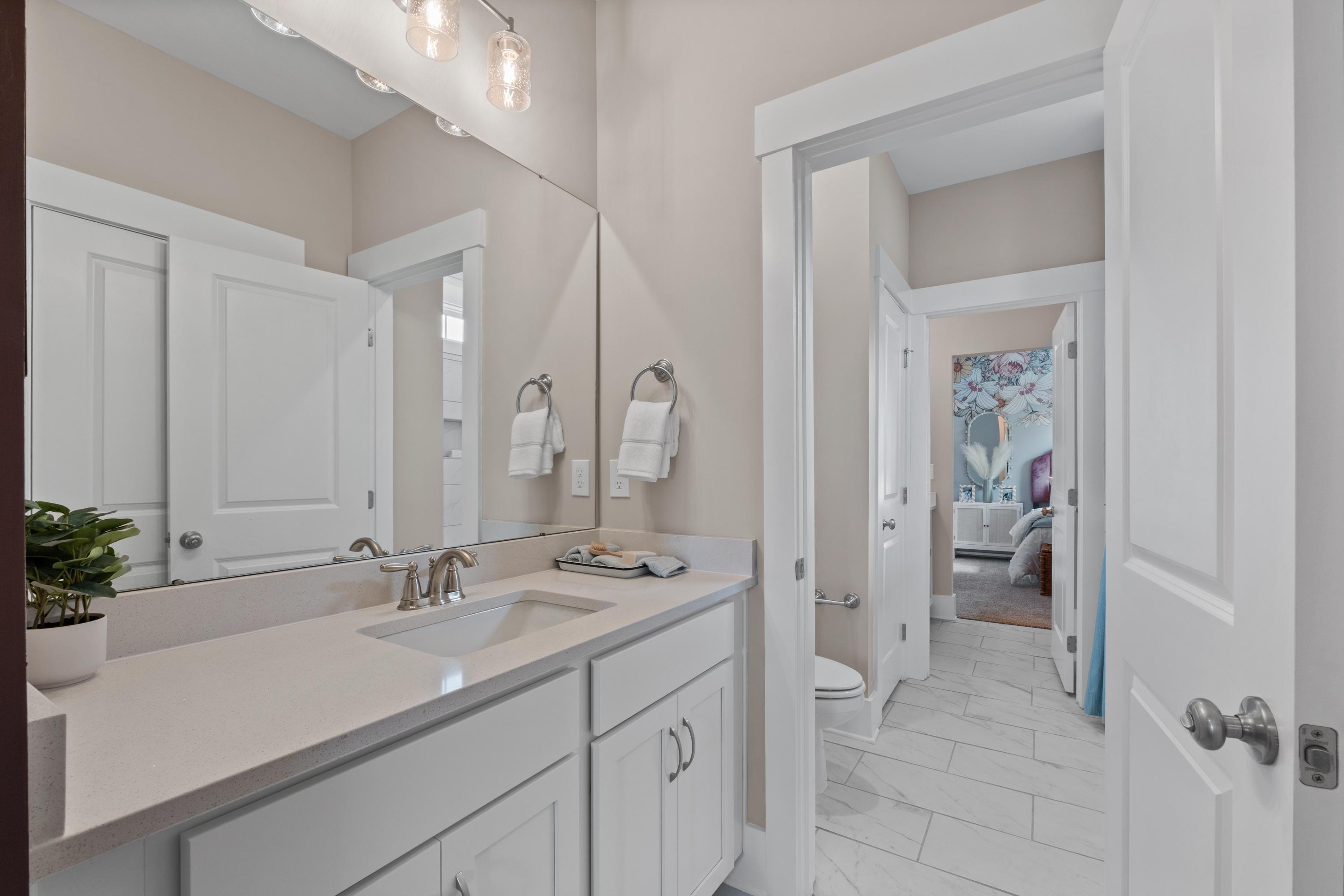 Spacious primary bathroom in Creekside, Harvest AL with white shaker vanity, quartz countertop, and open bedroom view