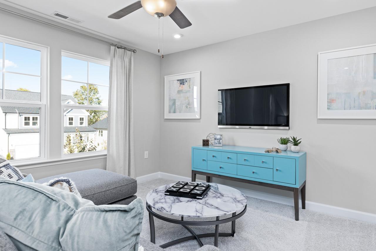 Bright loft area in The Hemlock A floor plan featuring a blue media console, marble coffee table, and wall-mounted TV.