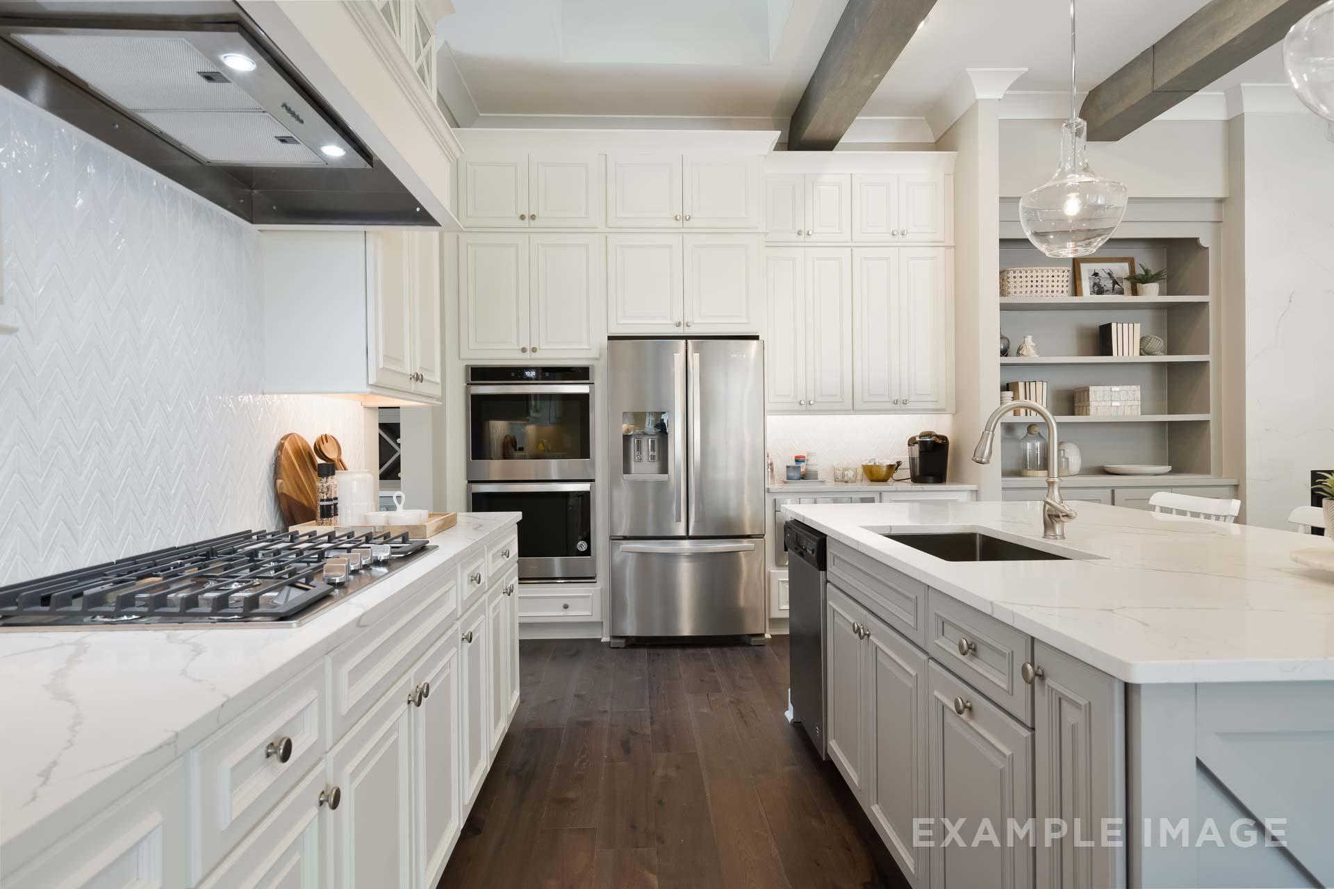 Spacious white shaker kitchen in The Seaside C with quartz island, stainless appliances, herringbone backsplash