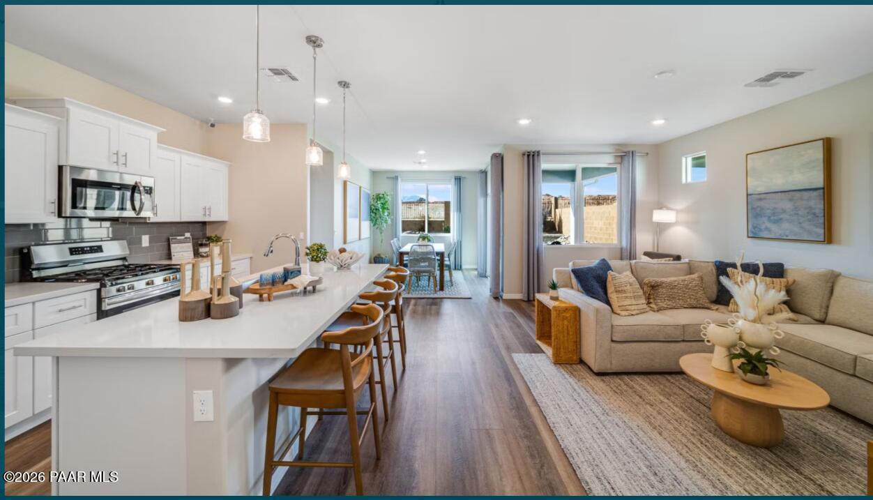 Open-concept kitchen with white quartz island, stainless appliances, dining area, and living room in The Newport B, Prescott AZ