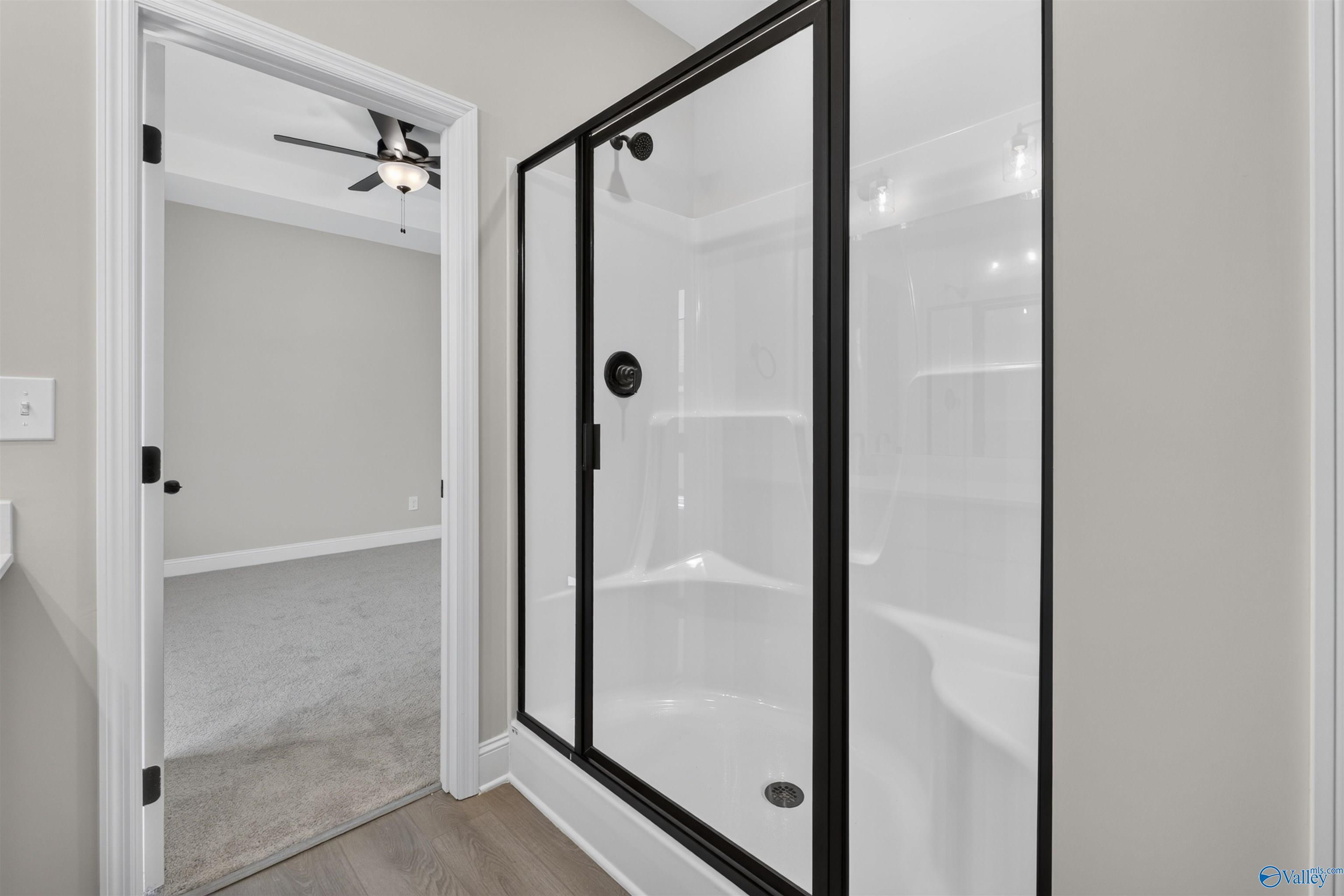 Modern bathroom with black-framed glass shower and soaking tub in Davidson Homes The Butler plan, Hazel Green, Alabama