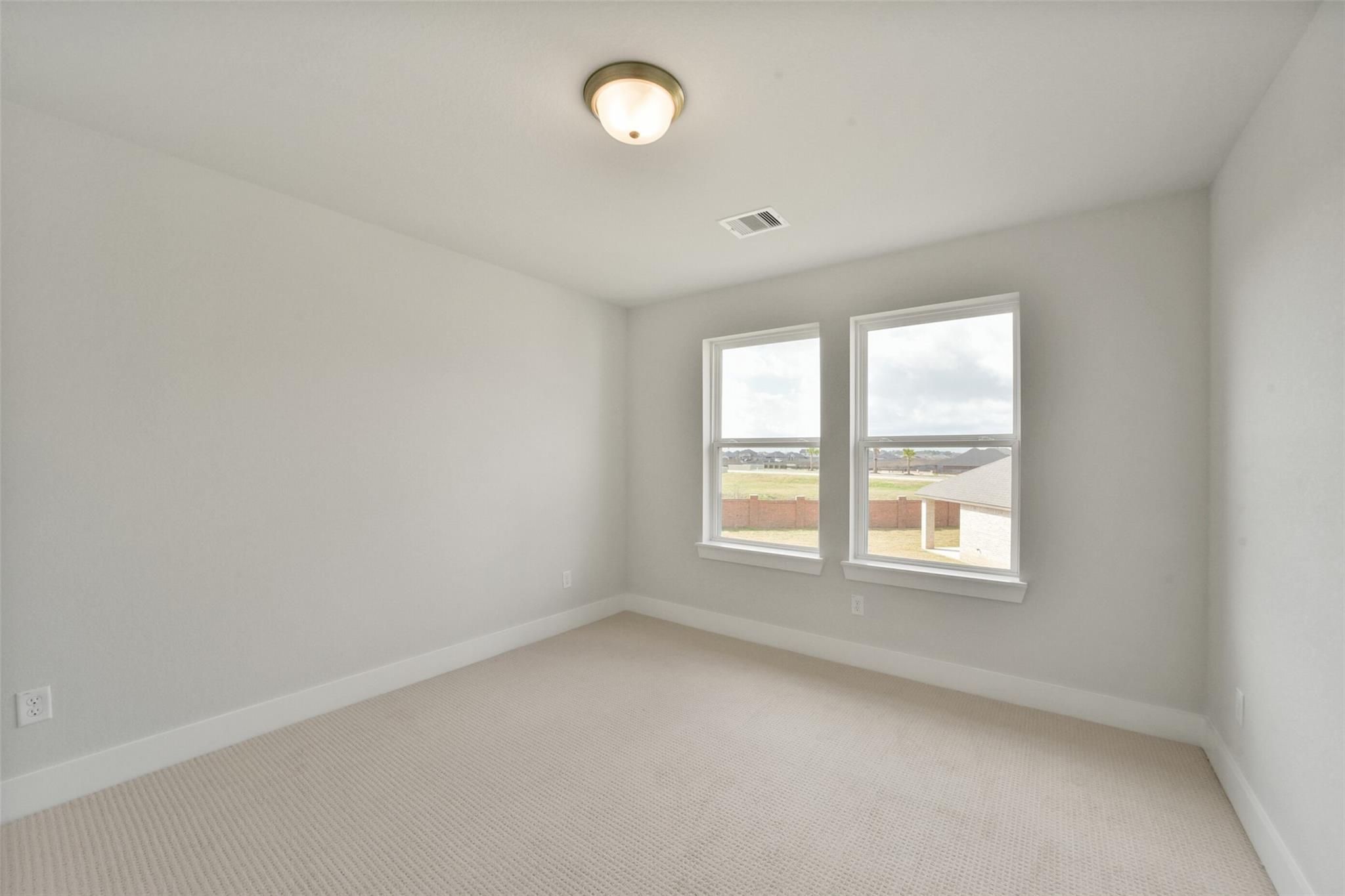 Bright secondary bedroom with beige walls, neutral carpet, large windows, and natural light in Davidson Homes The Zion A, Lago Mar, Texas City