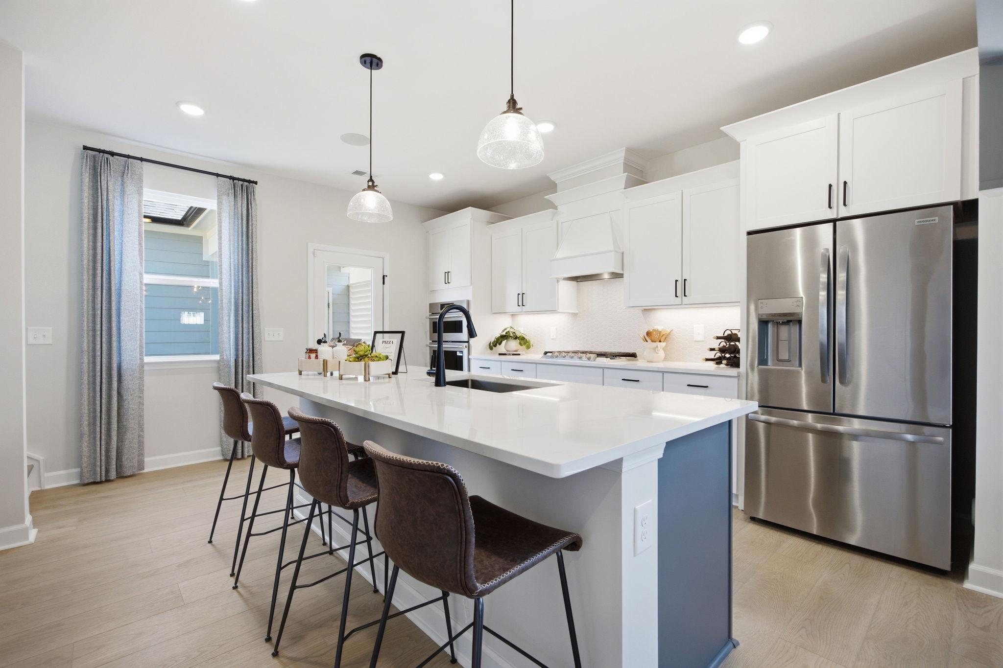 Modern white kitchen at Forestville Yard in Knightdale NC with quartz island, leather barstools, stainless appliances