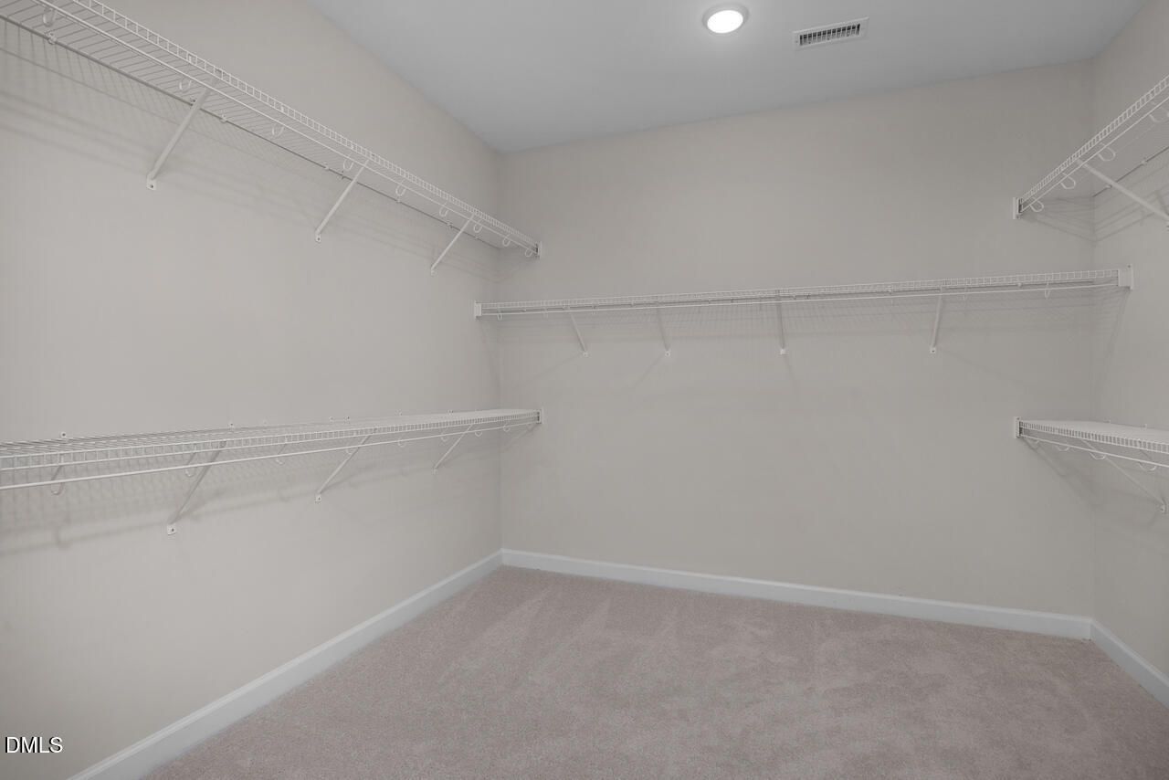 Spacious walk-in closet with wire shelving, neutral walls, and carpeted floor in Davidson Homes The Cypress D II, Angier, NC