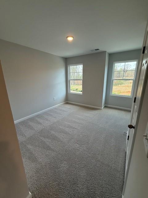 Bright secondary bedroom with gray walls, carpet flooring, and large windows overlooking woods in The Durham D, Cumming, GA