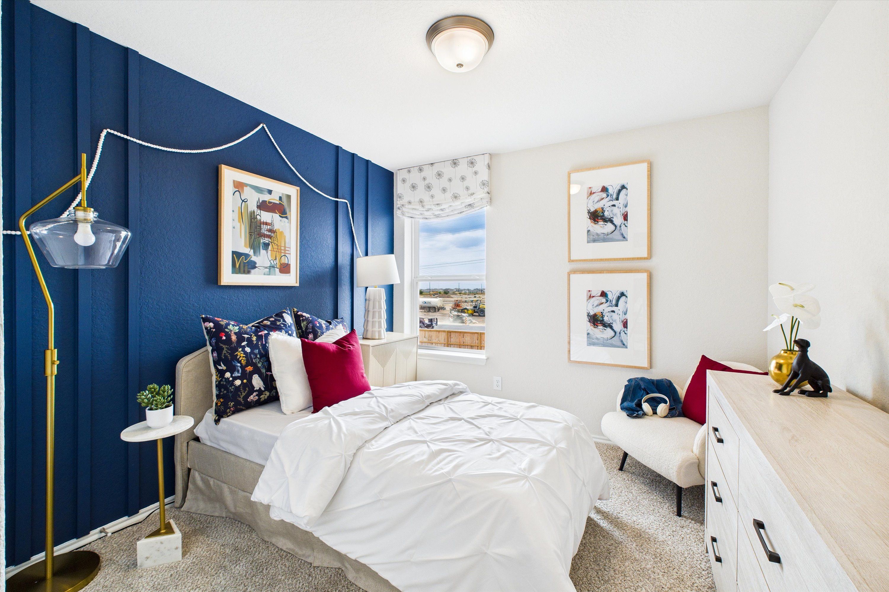 Cozy bedroom interior at Agave in San Antonio TX with navy accent wall, plush white bedding, gold lamp and artwork